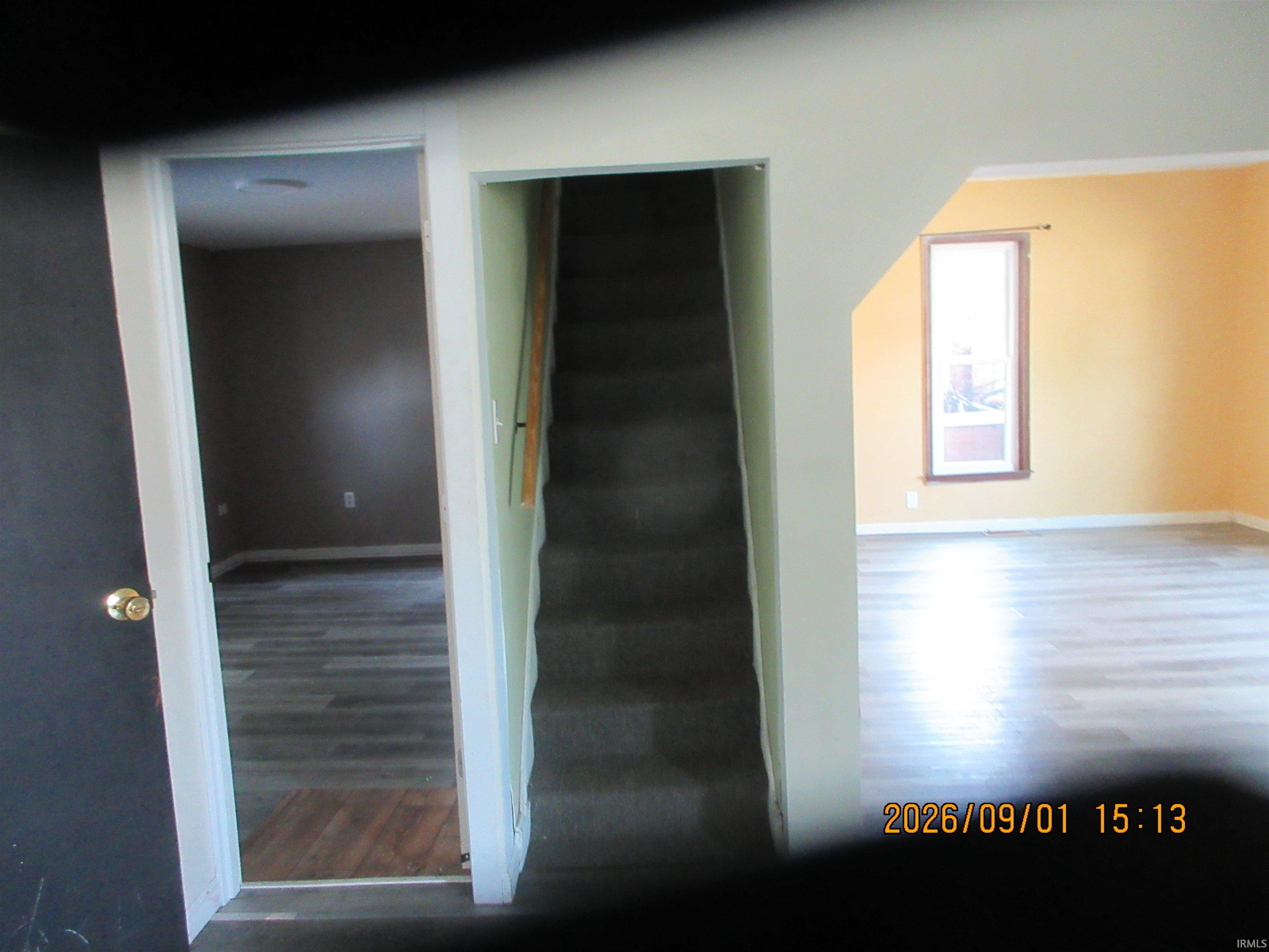 Interior with wood-finish flooring, a window with trim, and a carpeted staircase