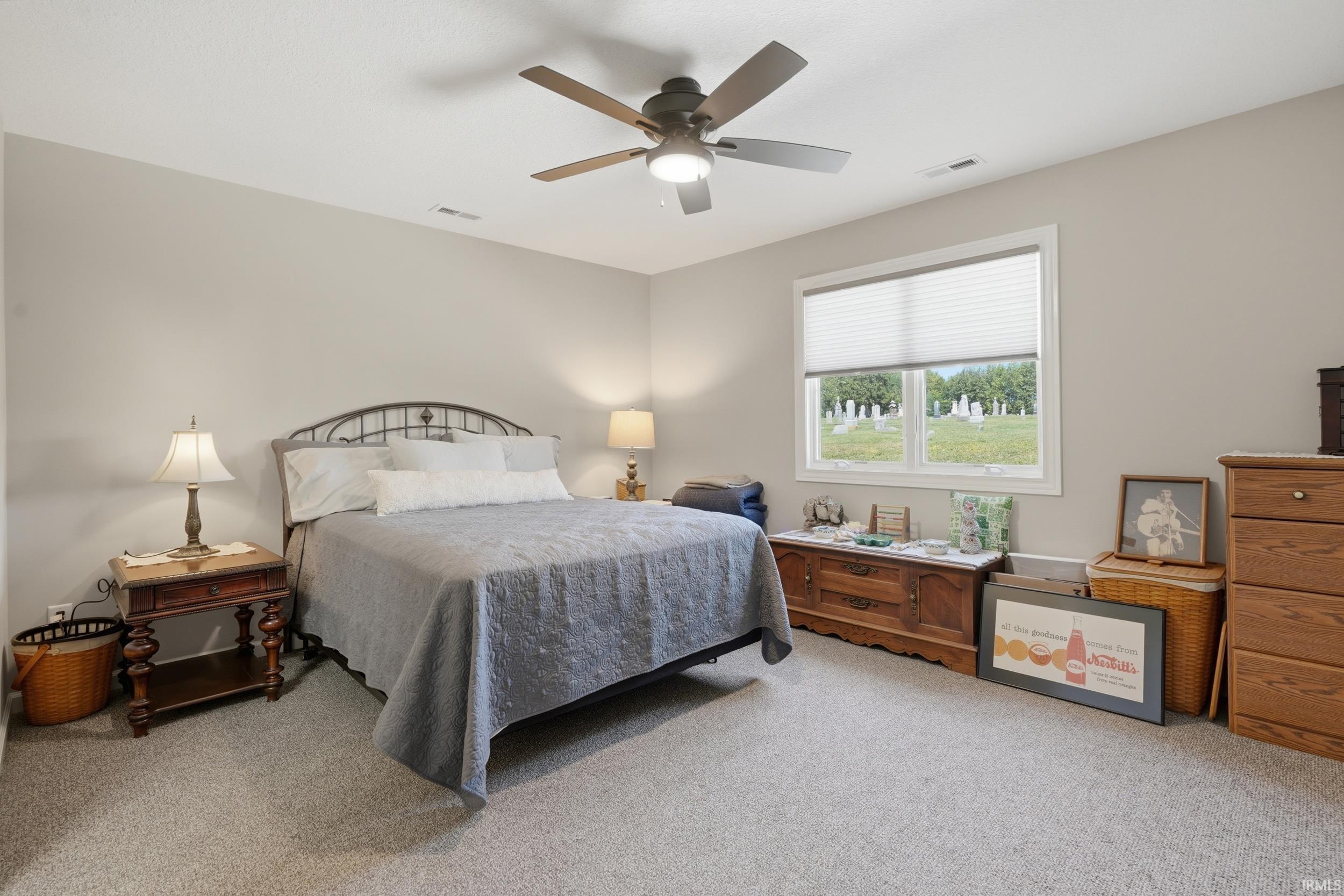 Carpeted flooring, neutral wall tones, window with horizontal blinds, and a ceiling fan with integrated lighting