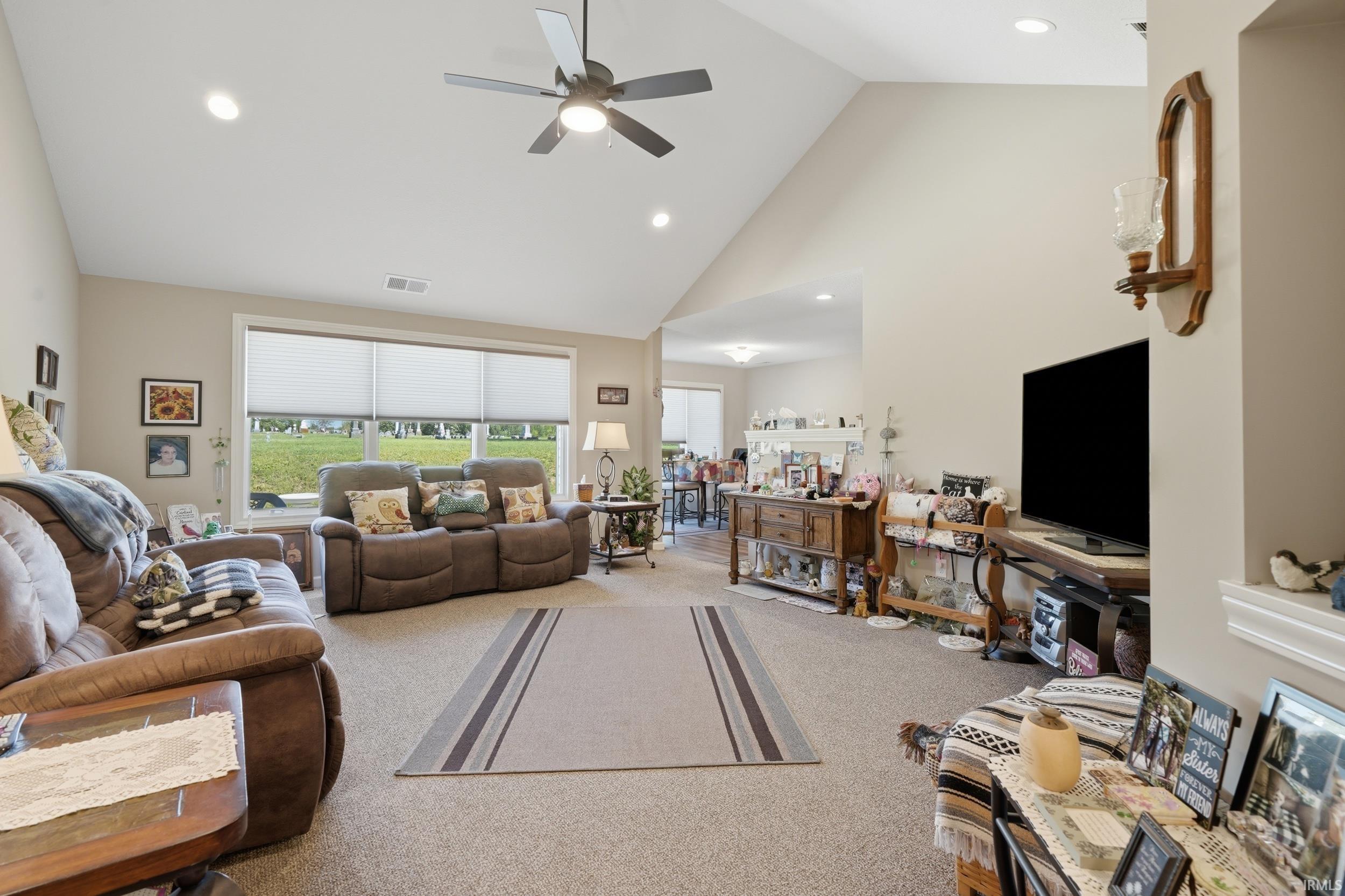 Vaulted ceiling, recessed lighting, ceiling fan, large windows, and carpet flooring