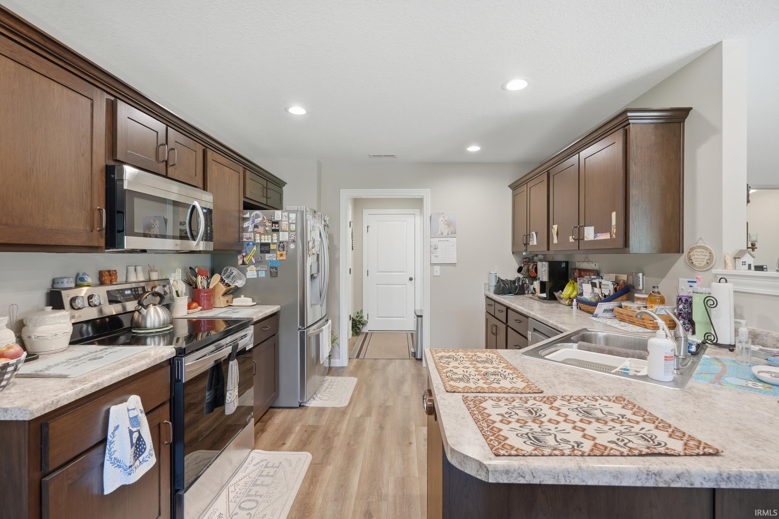 Kitchen featuring wood-finish flooring, recessed lighting, wood cabinetry, stone-finish countertops, and stainless-steel appliances