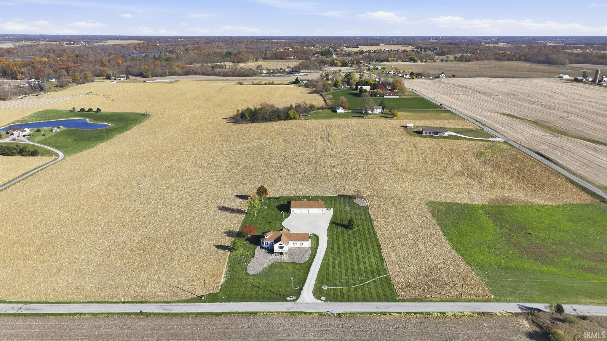 Expansive rural acreage featuring a manicured lawn, a paved driveway, and a detached structure