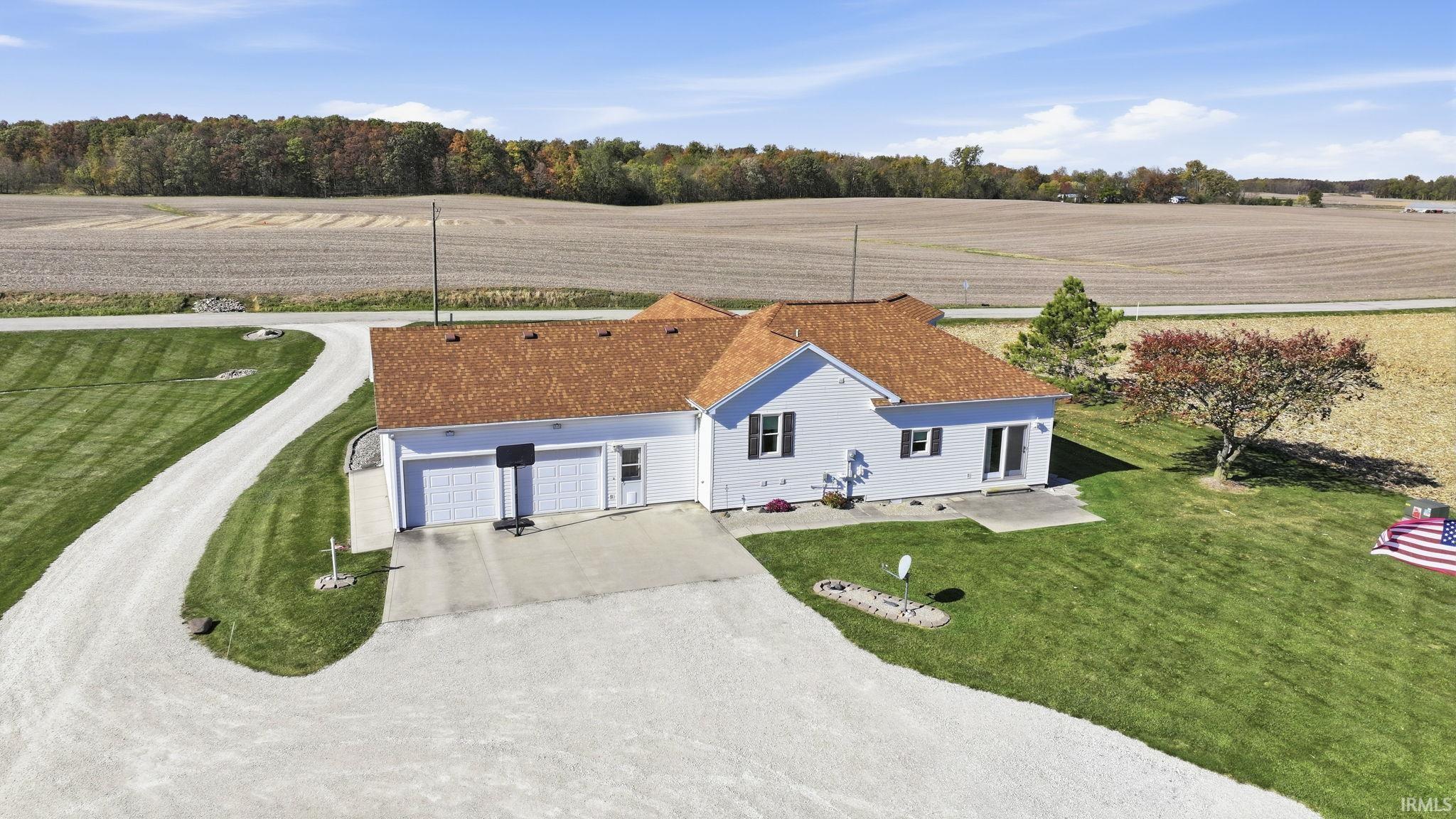 Single-story residence with a multi-gable asphalt shingle roof, white vinyl siding, an attached two-car garage, and a gravel driveway situated on a landscaped lot