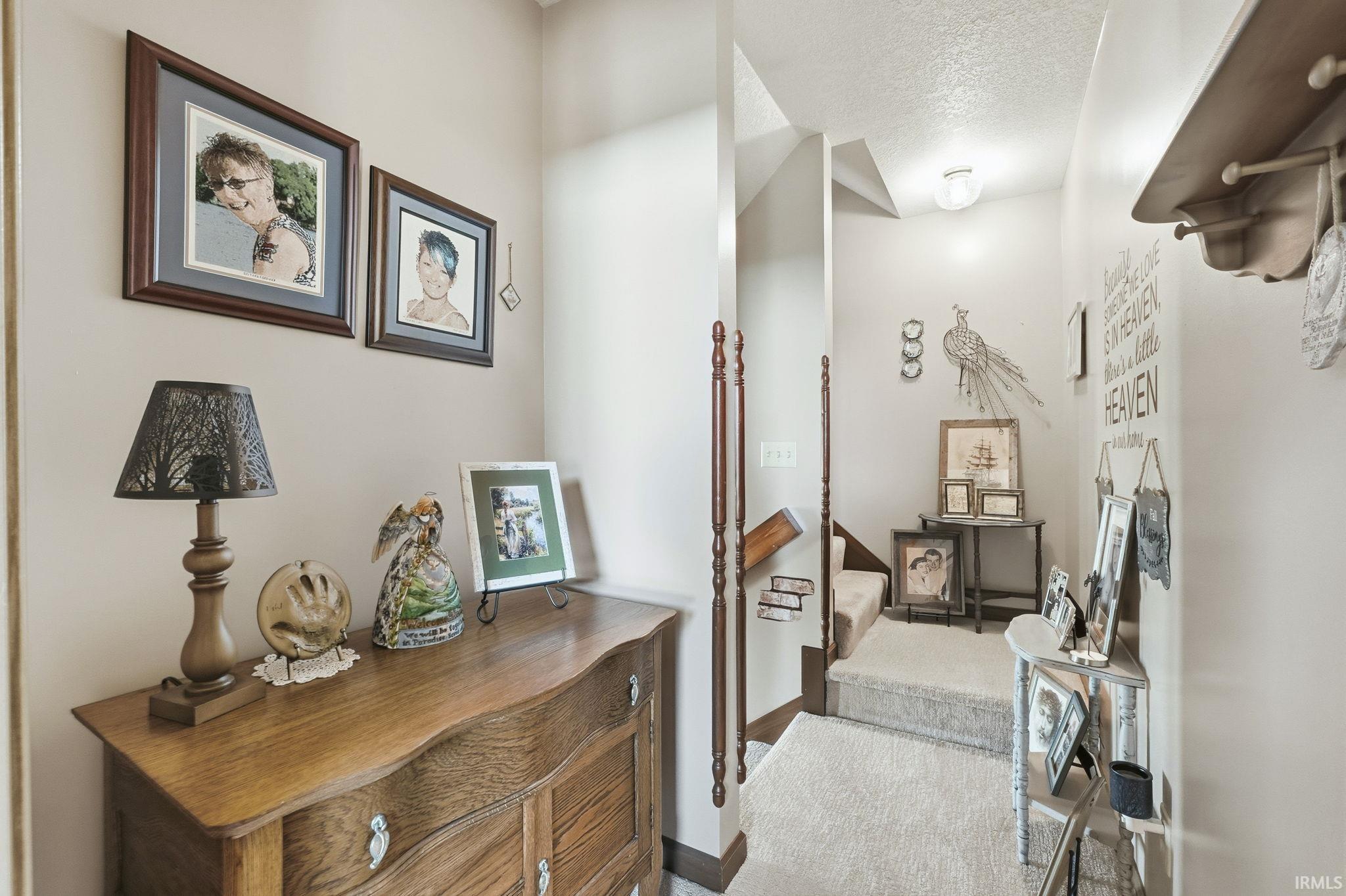 Entryway featuring neutral wall tones, carpeted stairs, and decorative wood railings
