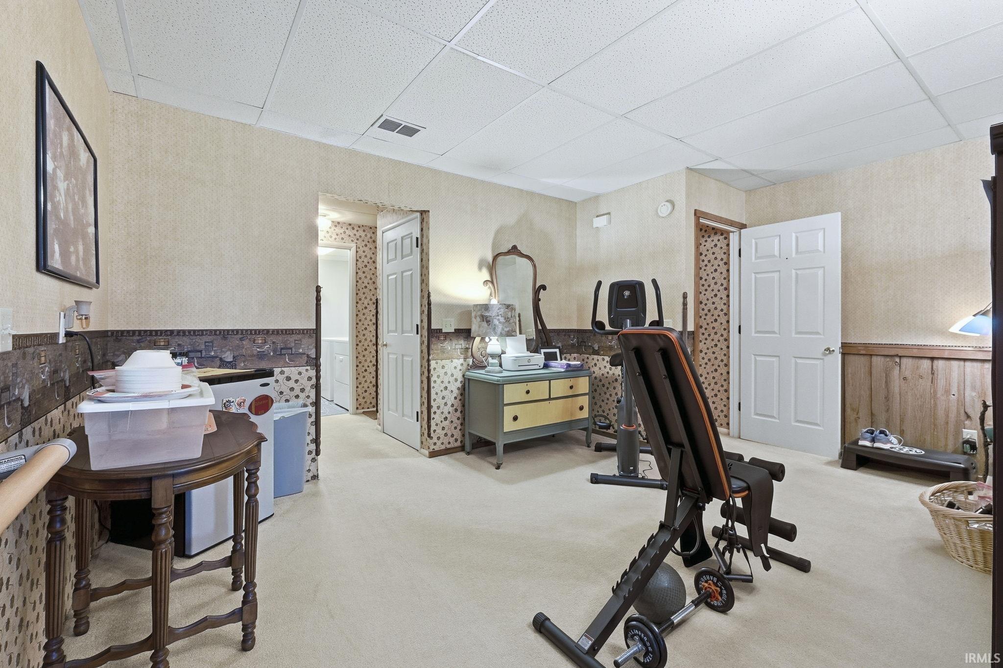 Finished interior space featuring textured wall coverings, wainscoting with decorative border, carpeted flooring, and white paneled interior doors