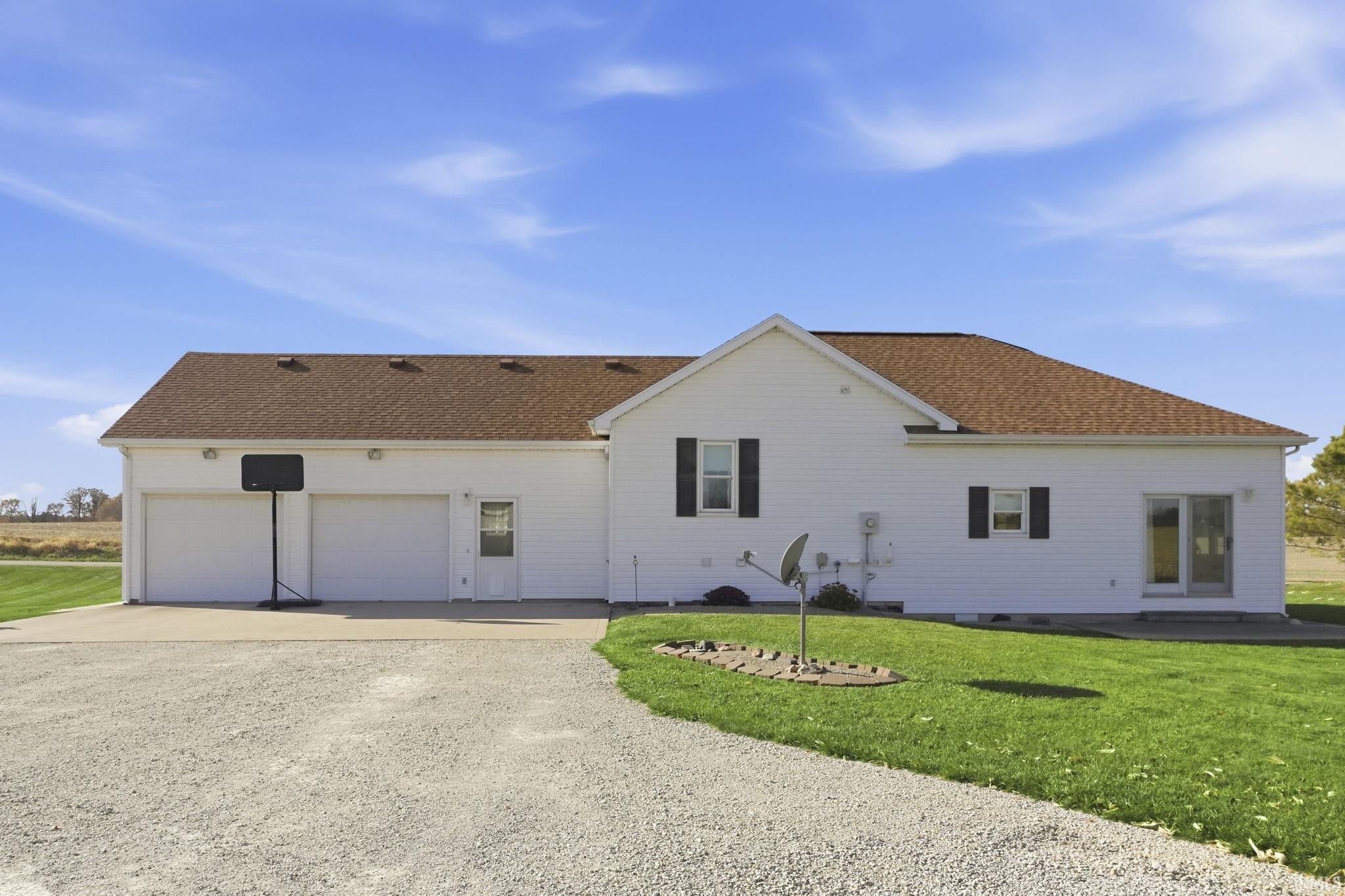 Exterior featuring white siding, a multi-gabled shingle roof, a two-car garage, and a gravel driveway