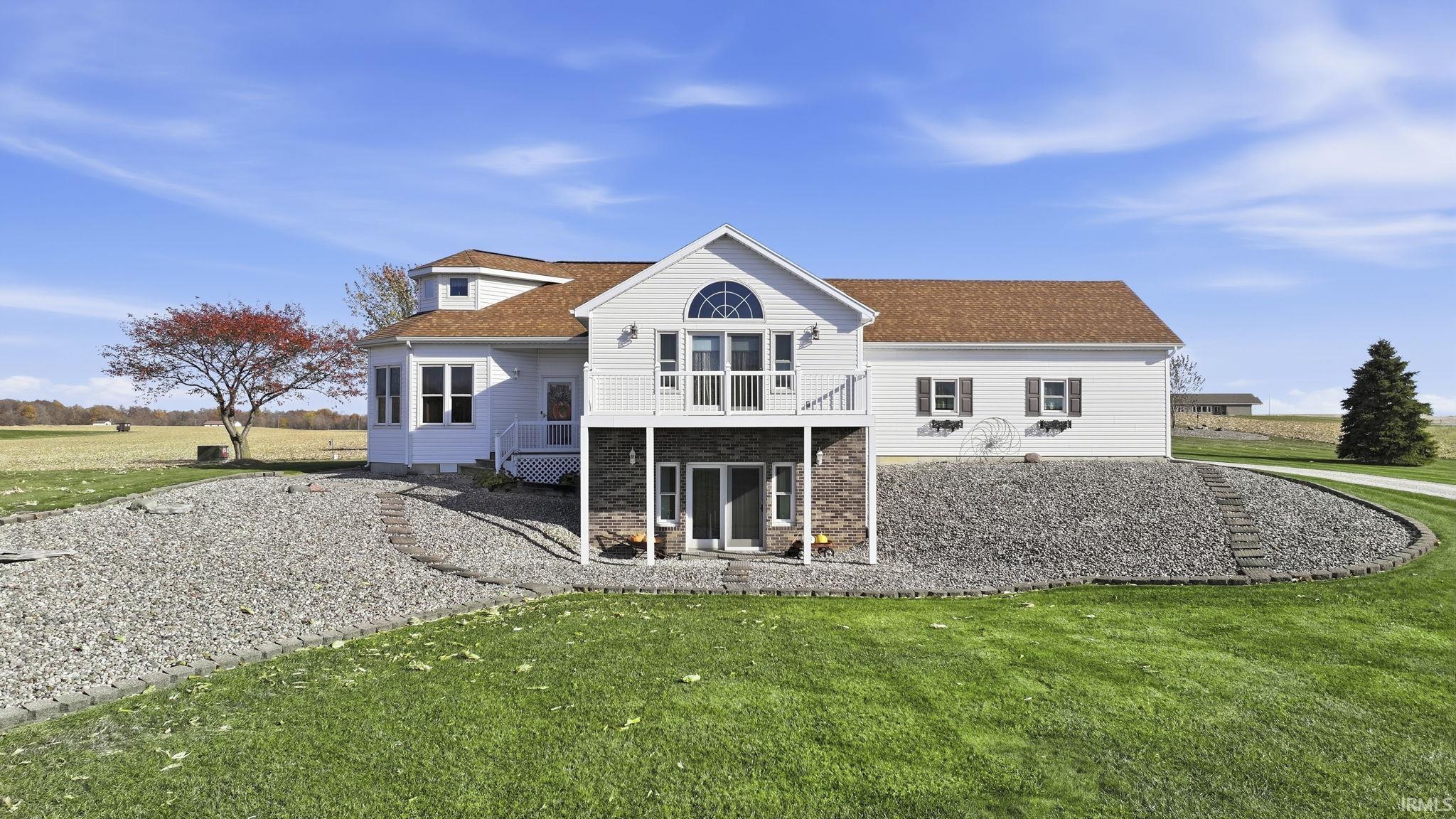 Multi-level exterior featuring white siding, a stone veneer foundation, an elevated wooden deck with railing, and a shingled roof