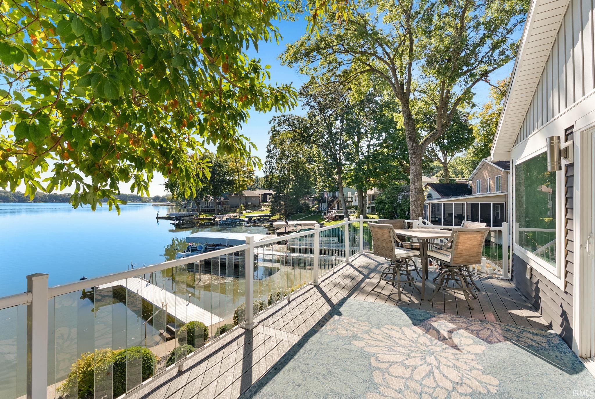 Composite deck with glass panel railing and water frontage featuring a dock