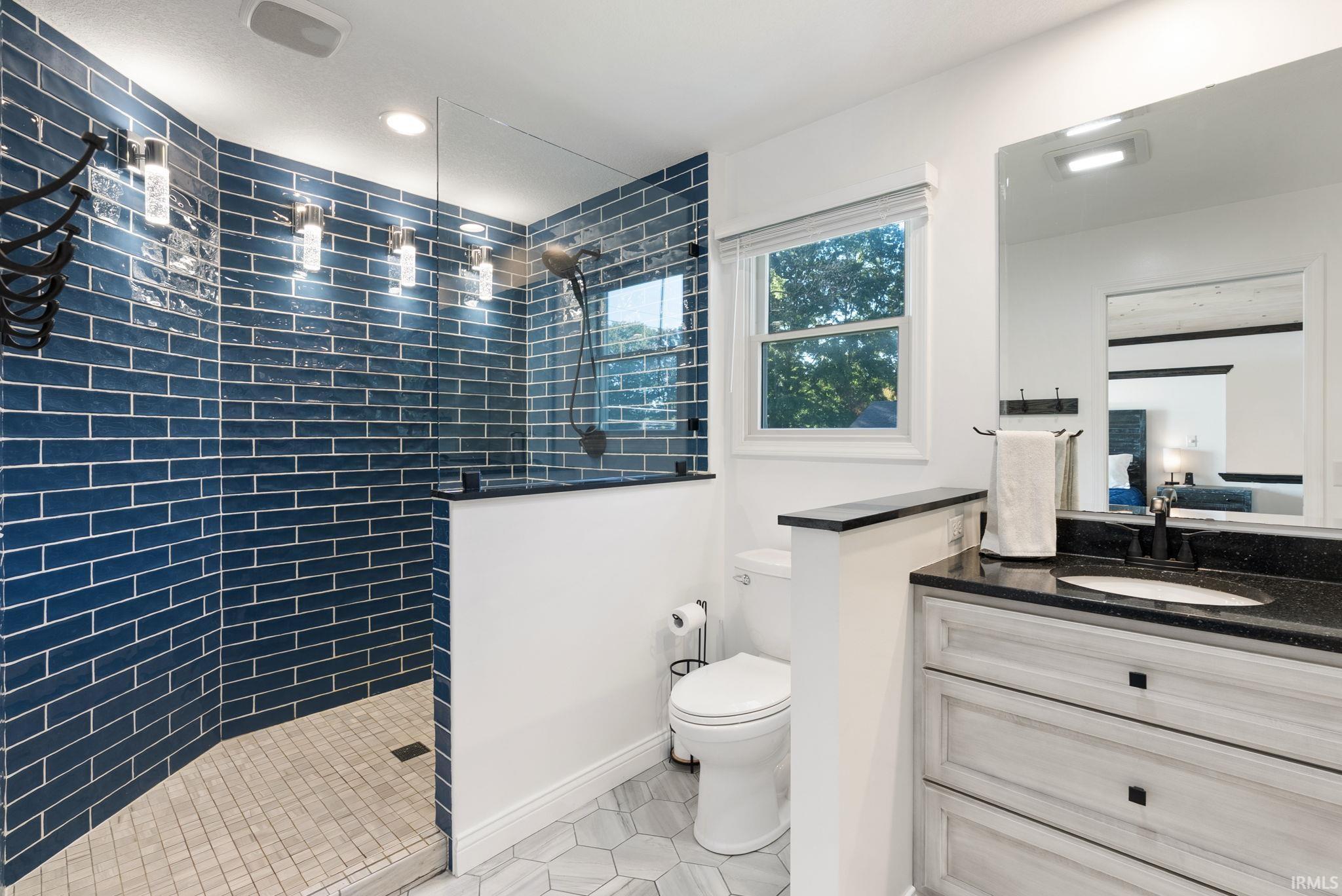 Shower featuring blue subway tile, glass enclosure, and a handheld showerhead