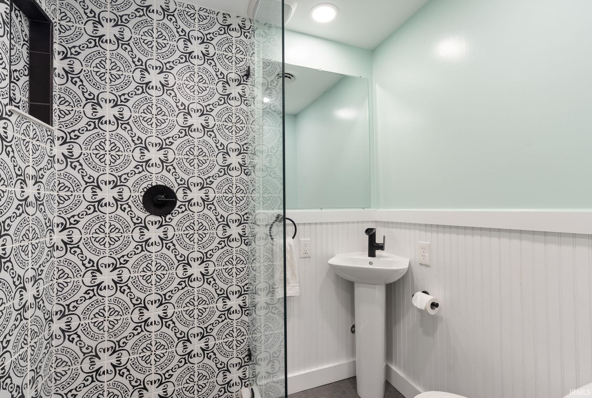 Shower enclosure with patterned wall tile and matte black fixtures