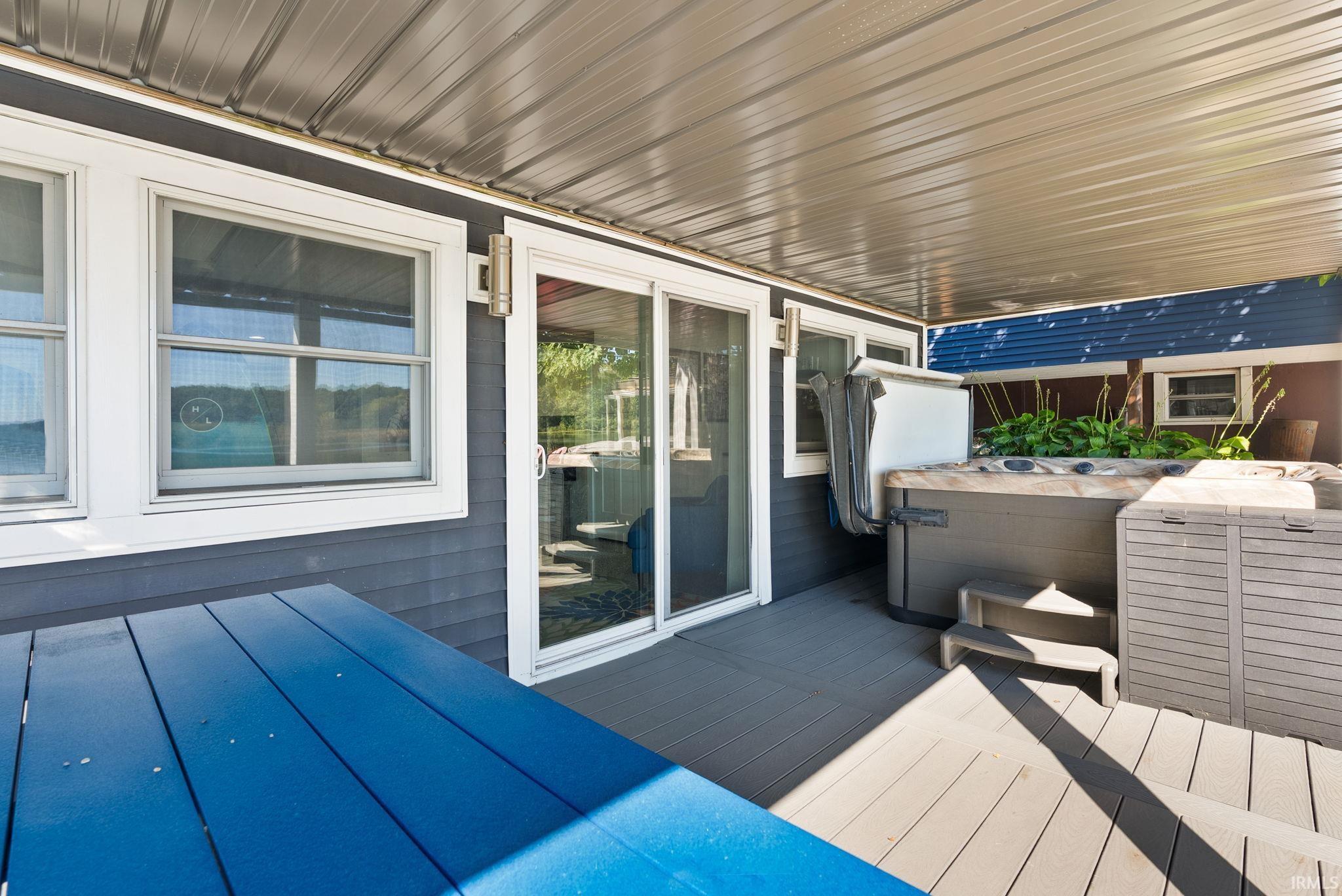 Covered deck area featuring a built-in hot tub, durable composite decking, and sliding glass doors