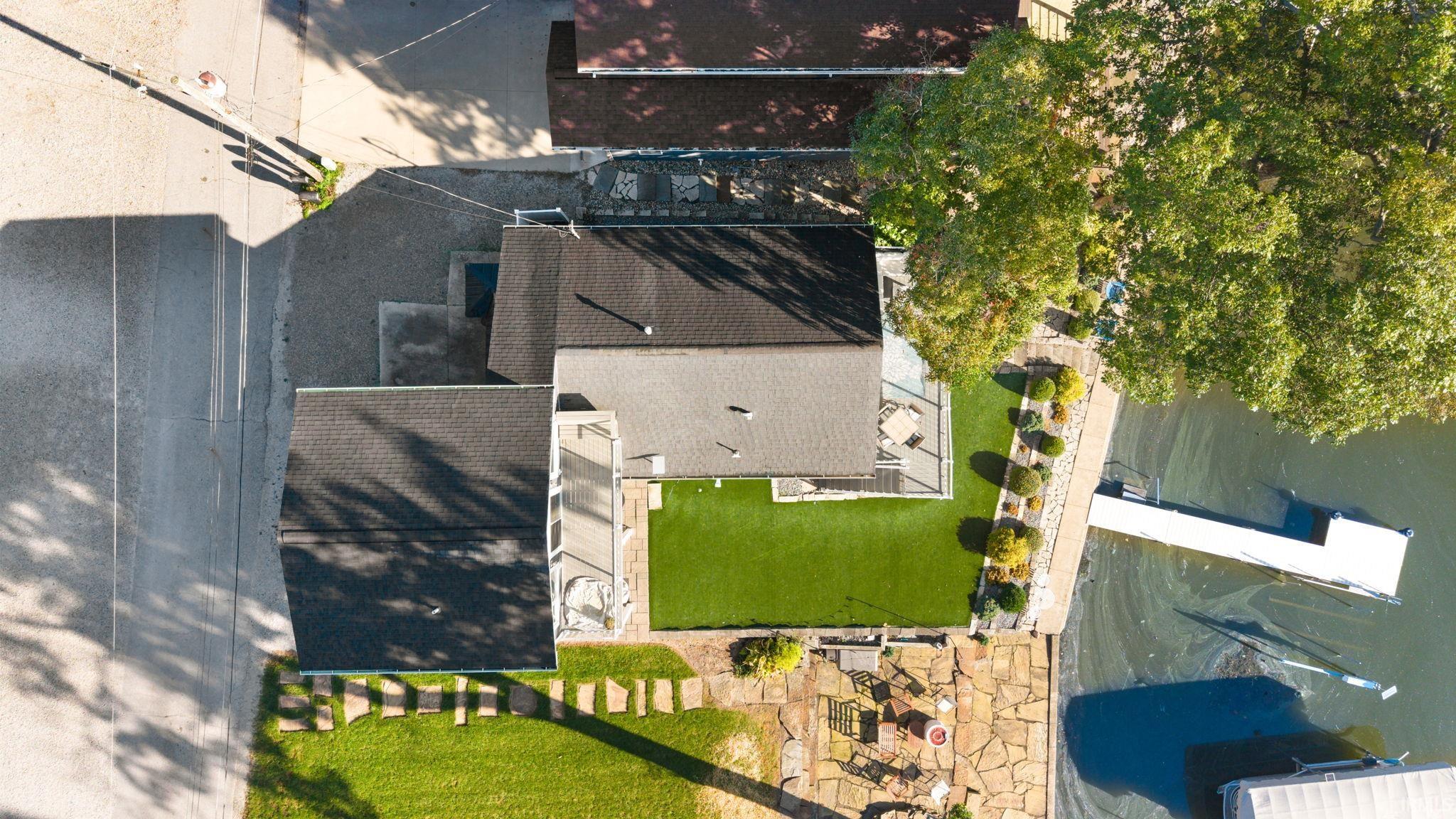 Waterfront property featuring a private dock, green lawn, and mature trees