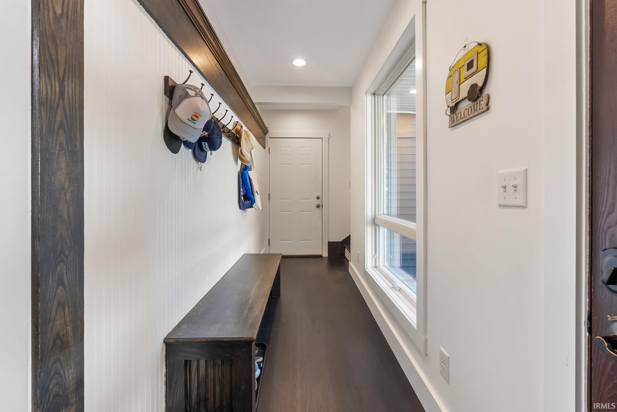 Entryway featuring dark wood-finish flooring, beadboard wall paneling, built-in coat rack, and recessed lighting