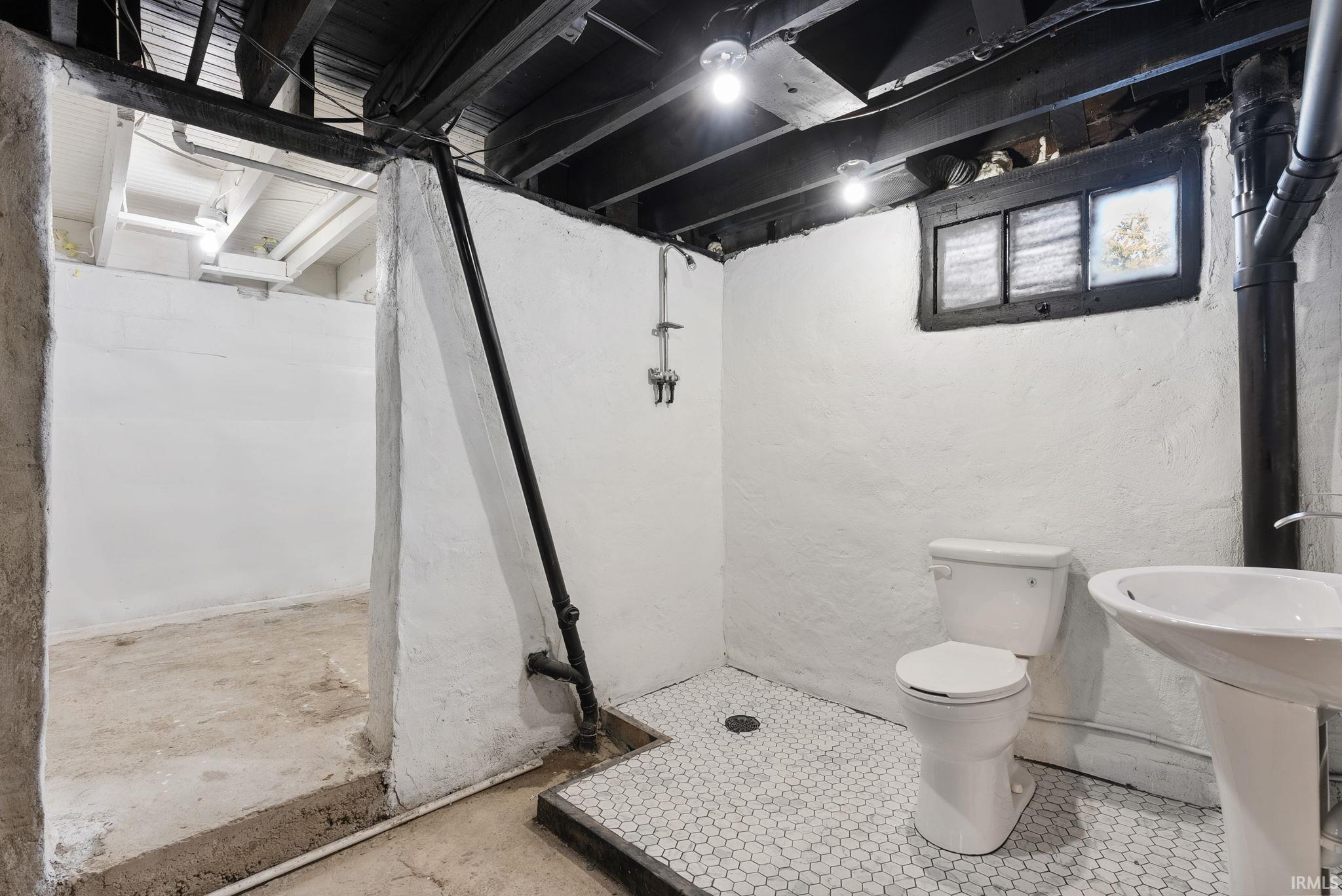 Utility area featuring painted masonry walls, hexagonal tile flooring, a pedestal sink, and a toilet