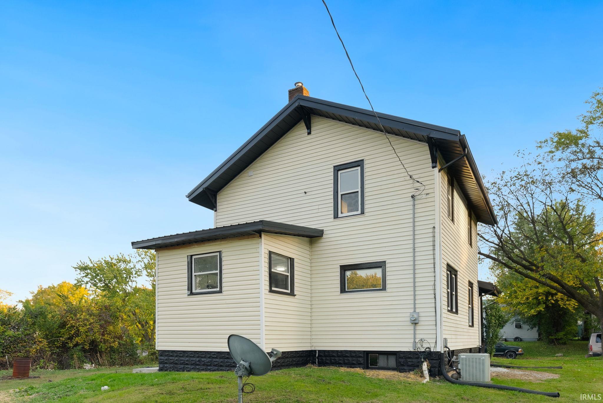 Two-story exterior featuring light-colored horizontal siding, a pitched roofline, dark-toned trim, and a black-painted stone foundation