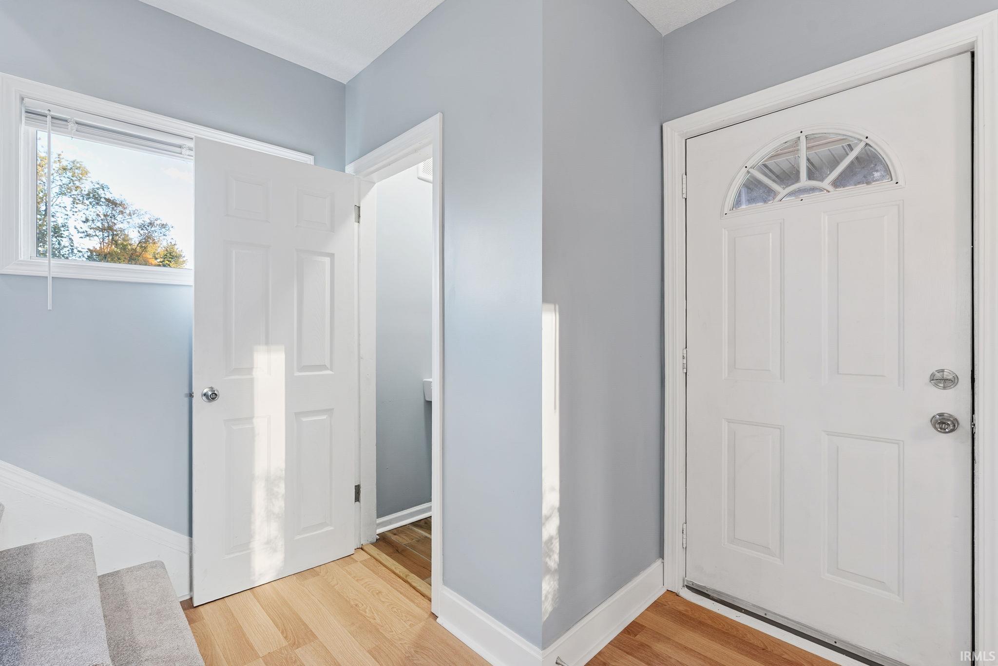 Entryway featuring wood-finish flooring, a six-panel exterior door with a semi-circular transom window, and neutral wall paint
