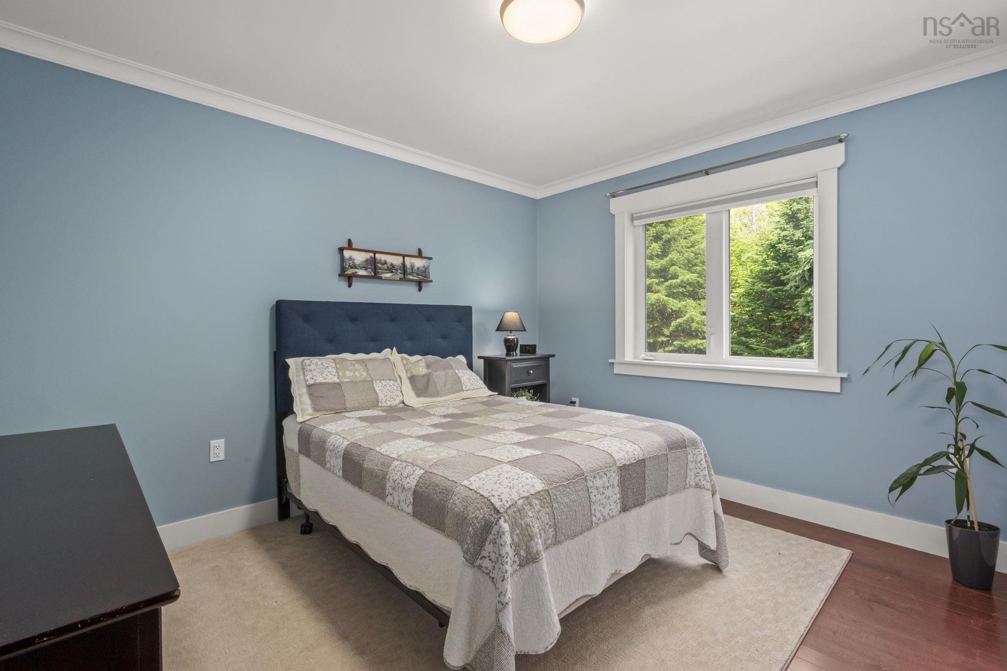 116 Whitecap Ridge, Black Point, NS (MLS® 202618413) — Bedroom featuring a window with exterior tree scenery, light blue walls, white crown molding, and wood-finish flooring