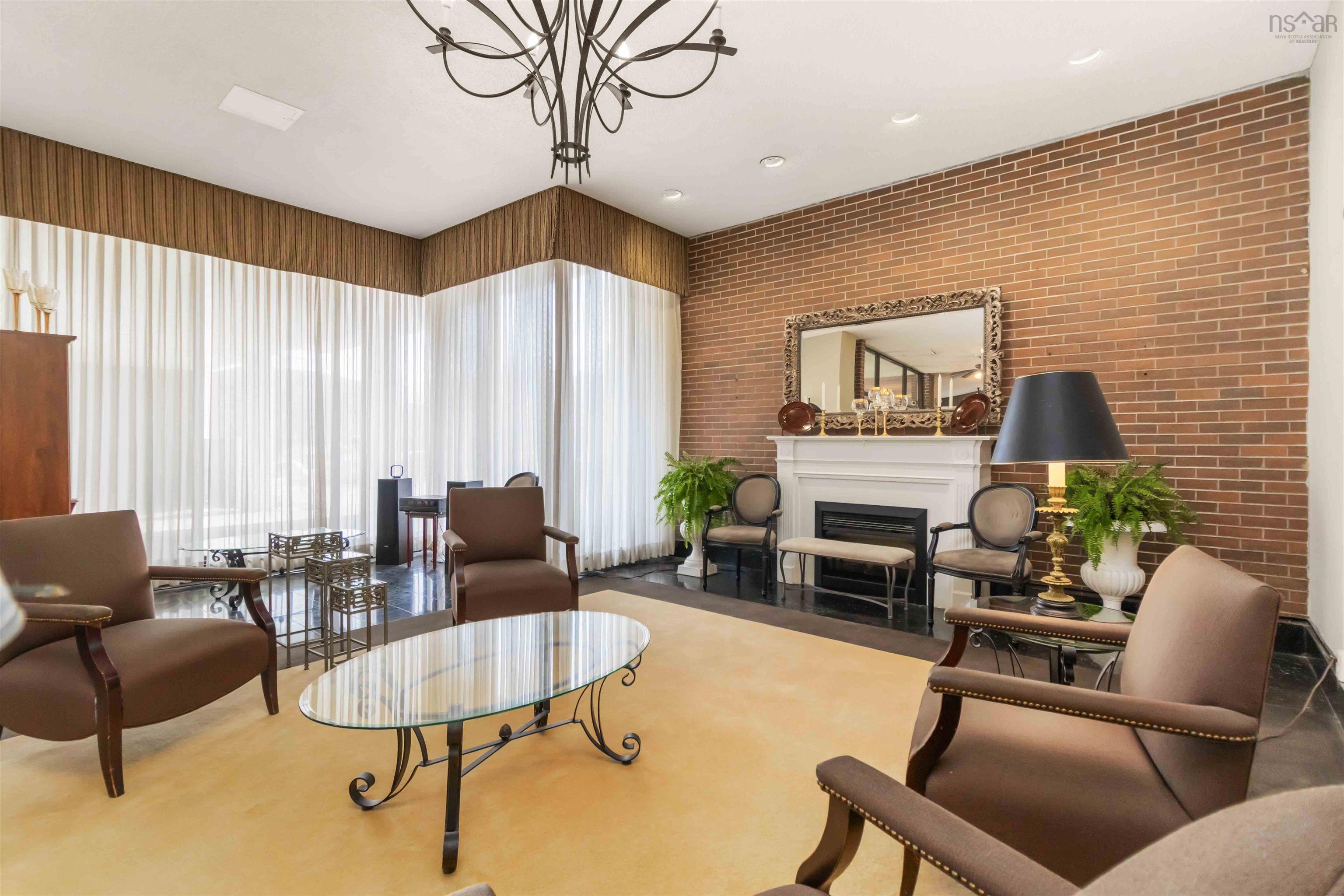 1601 5959 Spring Garden Road, Halifax, NS (MLS® 202620845) — Exposed brick wall, prominent fireplace with a white mantel, black tile flooring, and a decorative chandelier