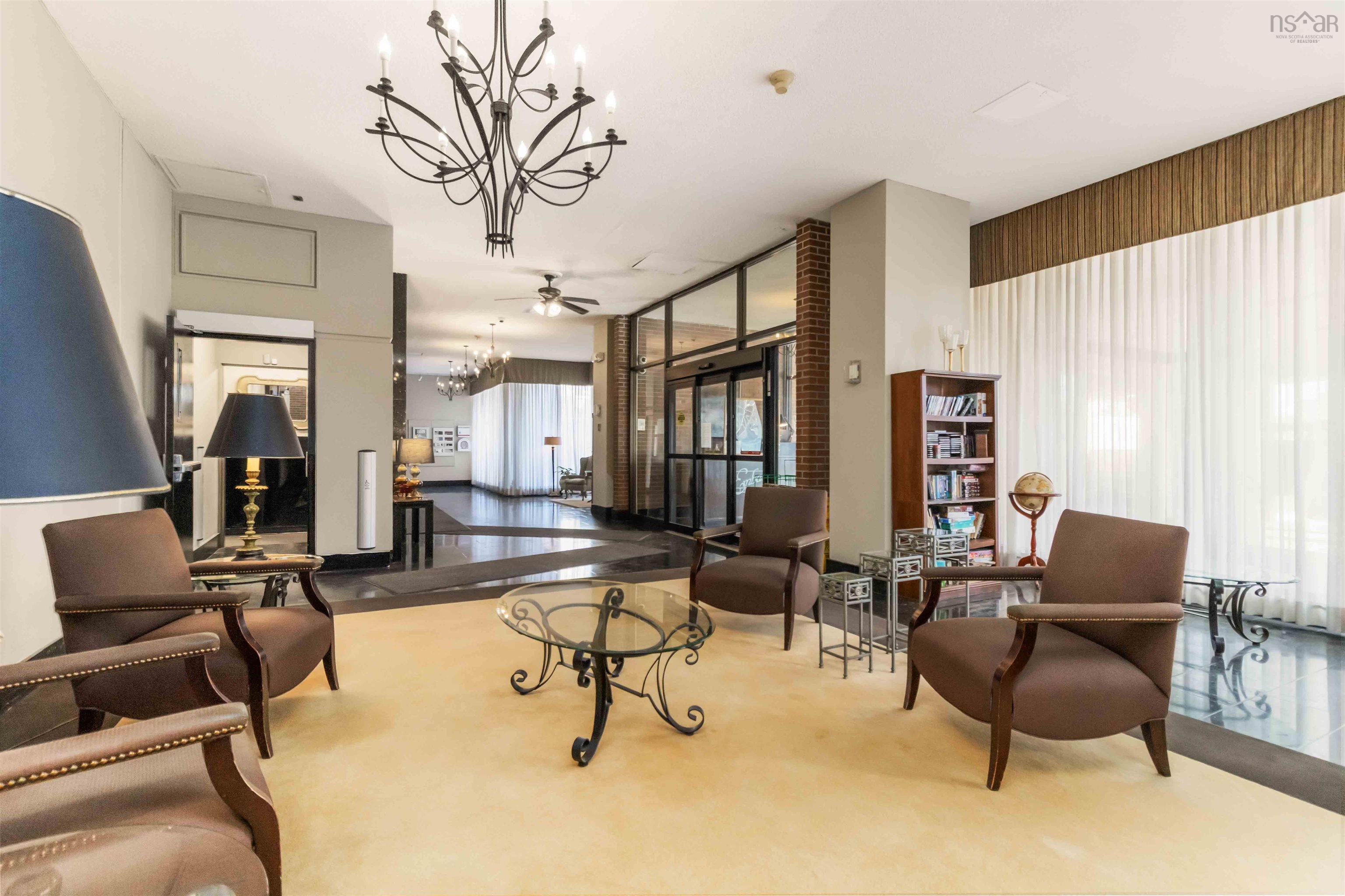 1601 5959 Spring Garden Road, Halifax, NS (MLS® 202620845) — Lobby with statement chandelier, dark-toned flooring, textured wall accents, and an expansive window with full-height drapery