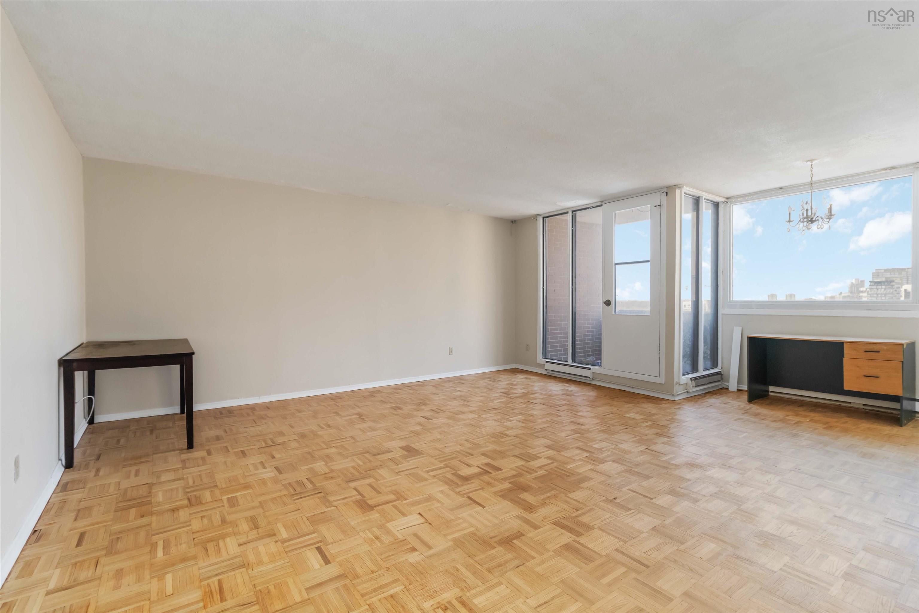 1601 5959 Spring Garden Road, Halifax, NS (MLS® 202620845) — Expansive living area featuring parquet wood flooring and a large window with a chandelier