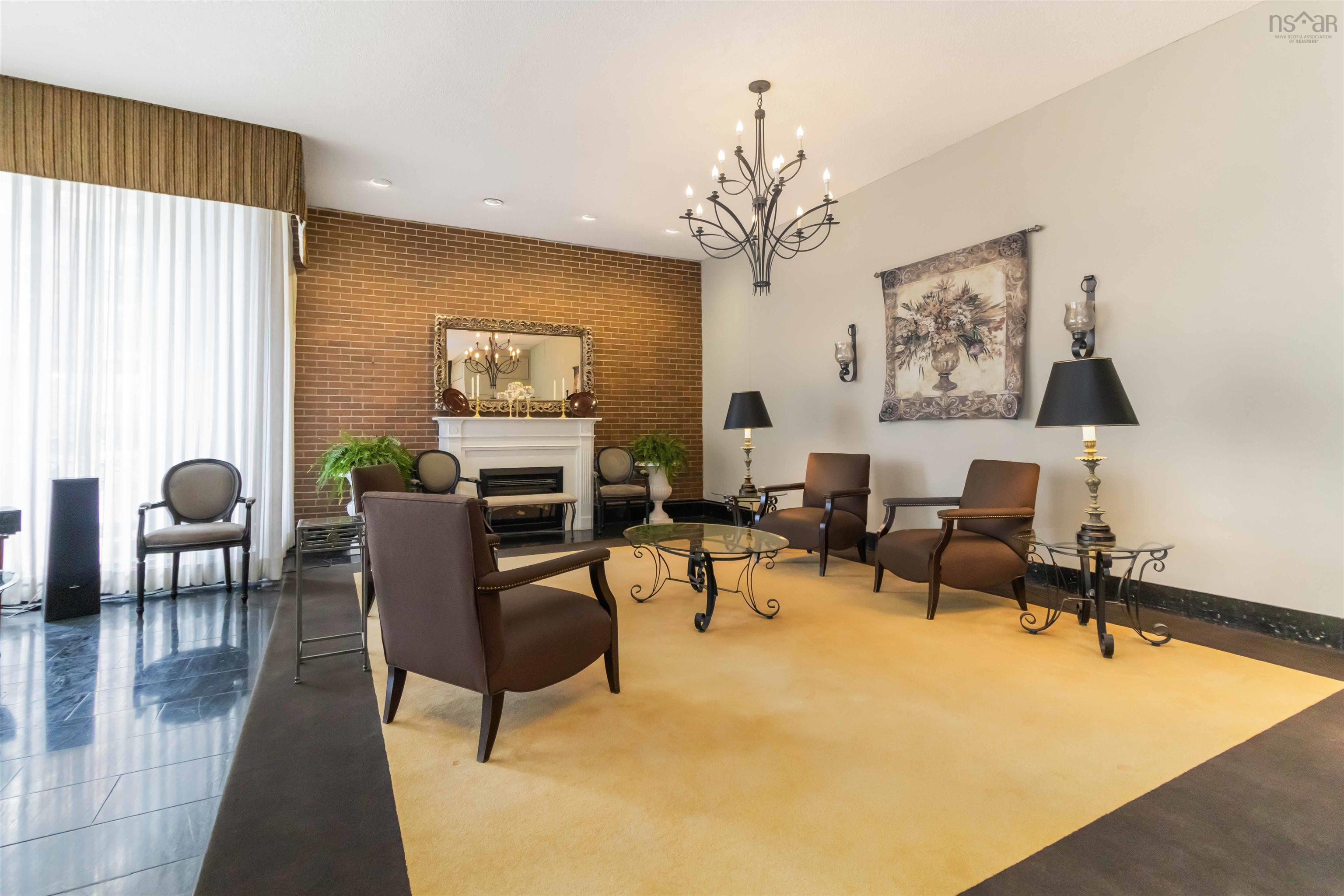 1601 5959 Spring Garden Road, Halifax, NS (MLS® 202620845) — Black polished stone flooring, exposed brick accent wall, white mantel fireplace, and a wrought iron chandelier