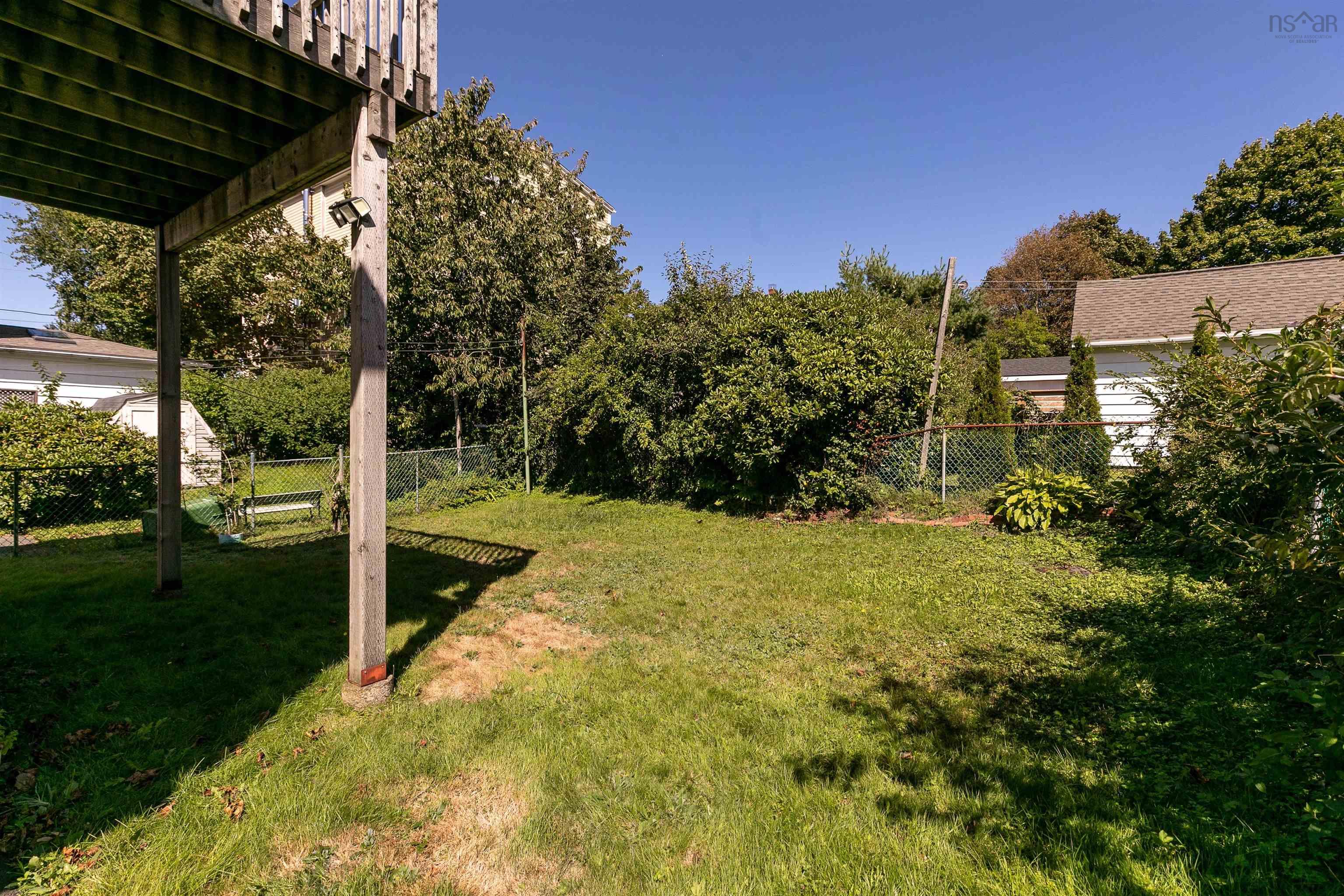 2875 Connaught Avenue, Halifax, NS (MLS® 202623267) — Expansive grassy yard with mature perimeter trees and chain-link fencing