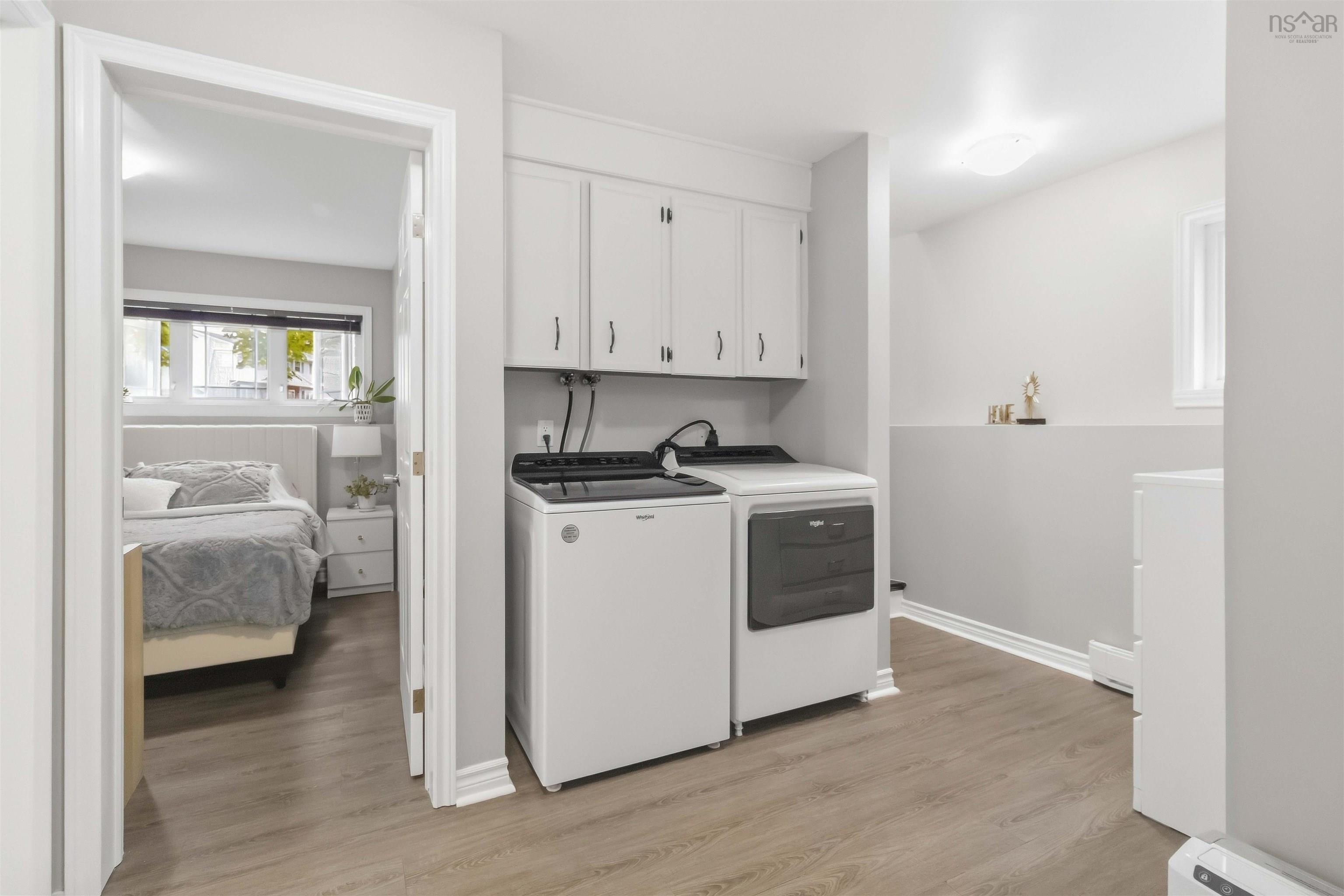 34 Lindsay Court, Lower Sackville, NS (MLS® 202624063) — Dedicated laundry area featuring upper cabinetry, light wood-finish flooring, a wall-mounted light fixture, and a window providing natural light