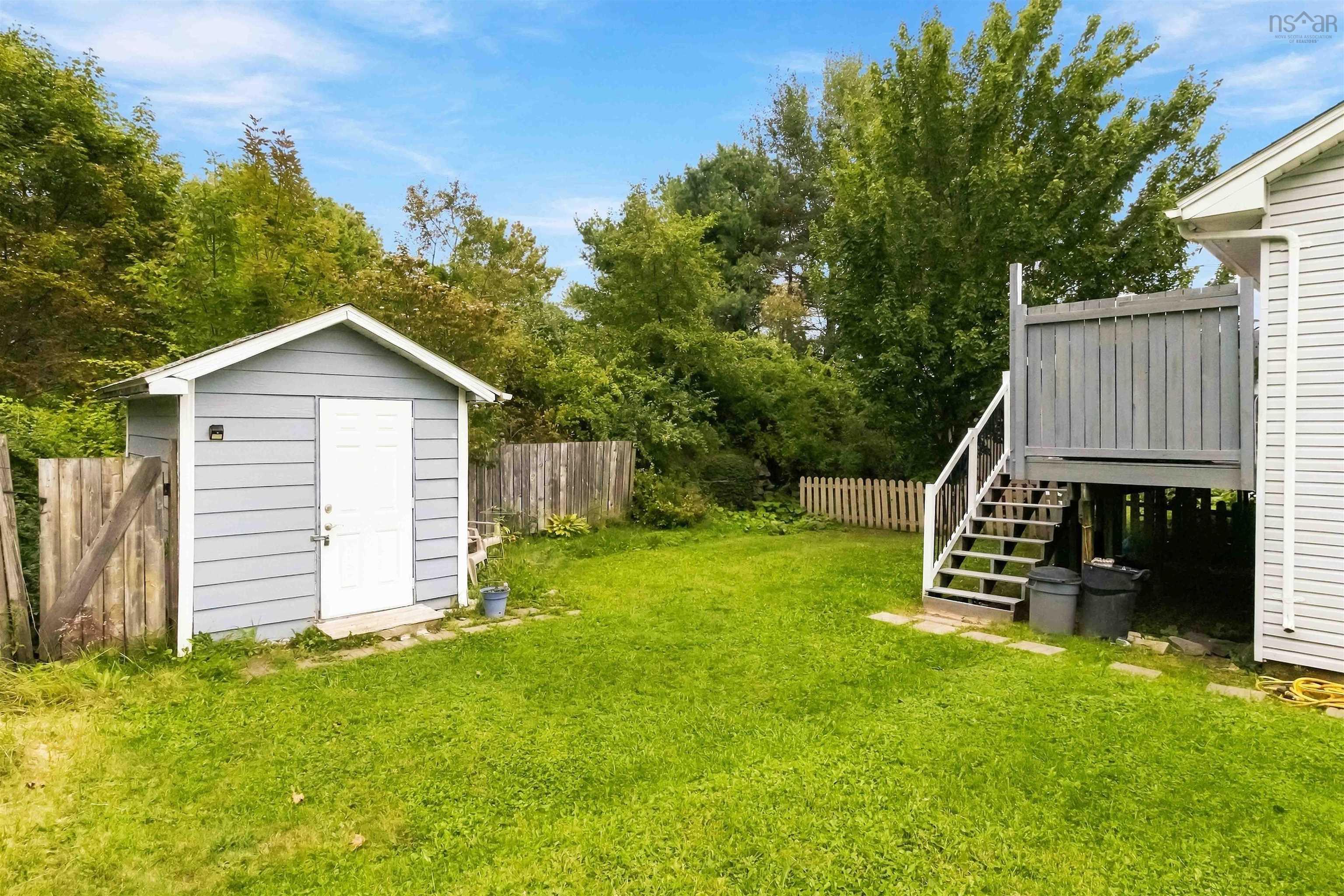 34 Lindsay Court, Lower Sackville, NS (MLS® 202624063) — Expansive backyard featuring a gray storage shed, a wooden deck with stairs, and perimeter fencing