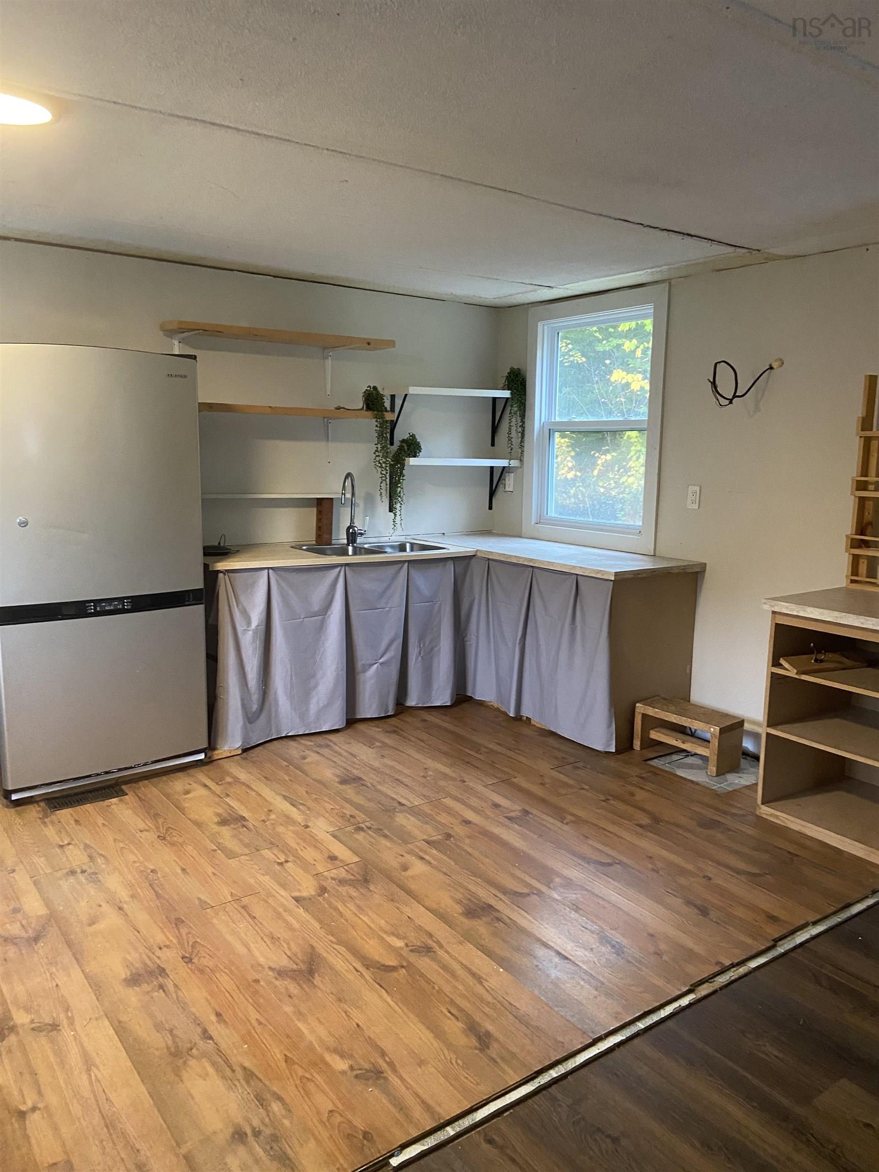 1126 Myra Road, Porters Lake, NS (MLS® 202624638) — Wood-finish flooring, built-in shelving, a stainless steel refrigerator, and a window