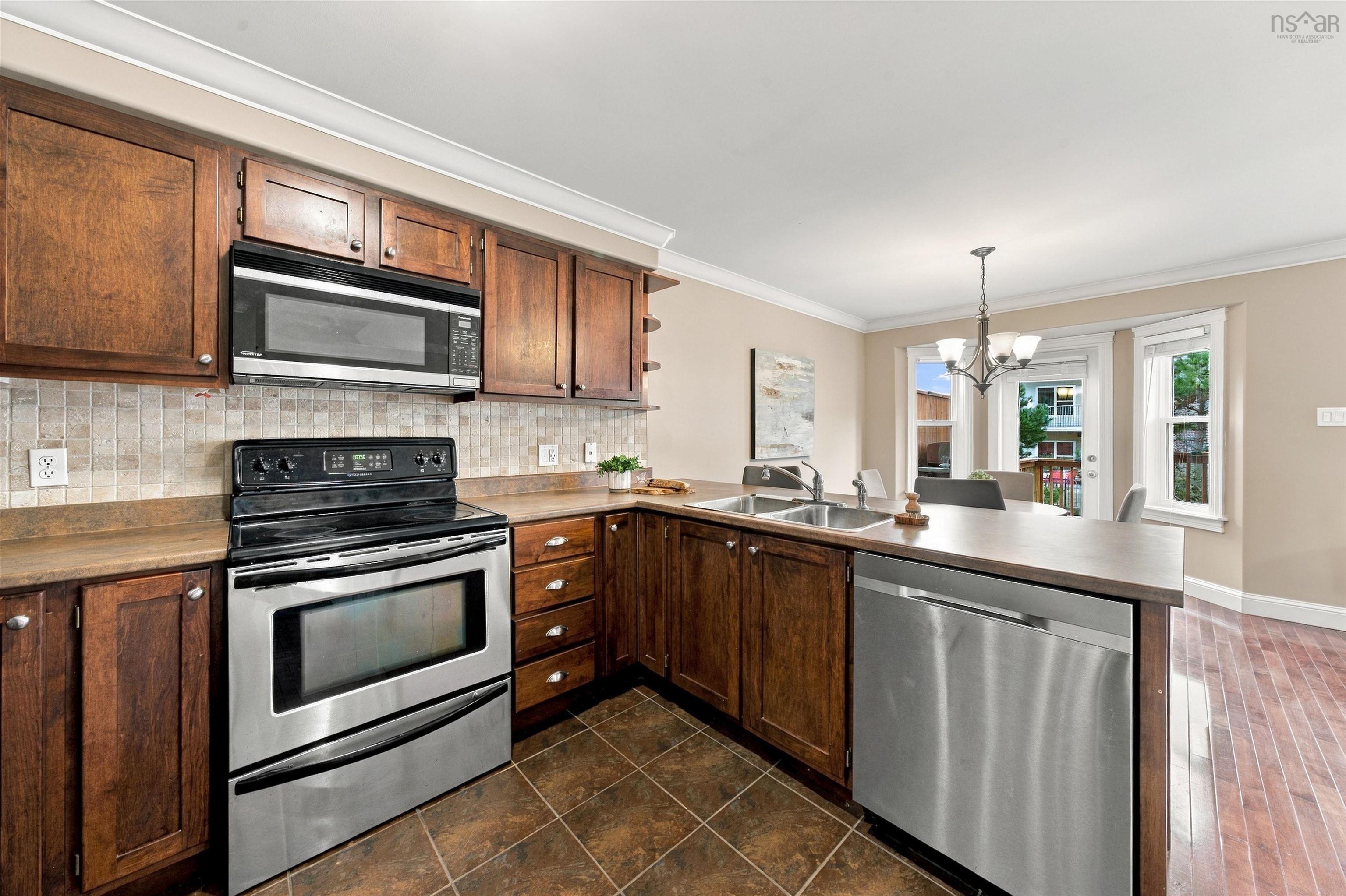 150 Transom Drive, Halifax, NS (MLS® 202625460) — Kitchen featuring wood cabinetry, stainless steel appliances, a tile backsplash, and wood-finish flooring