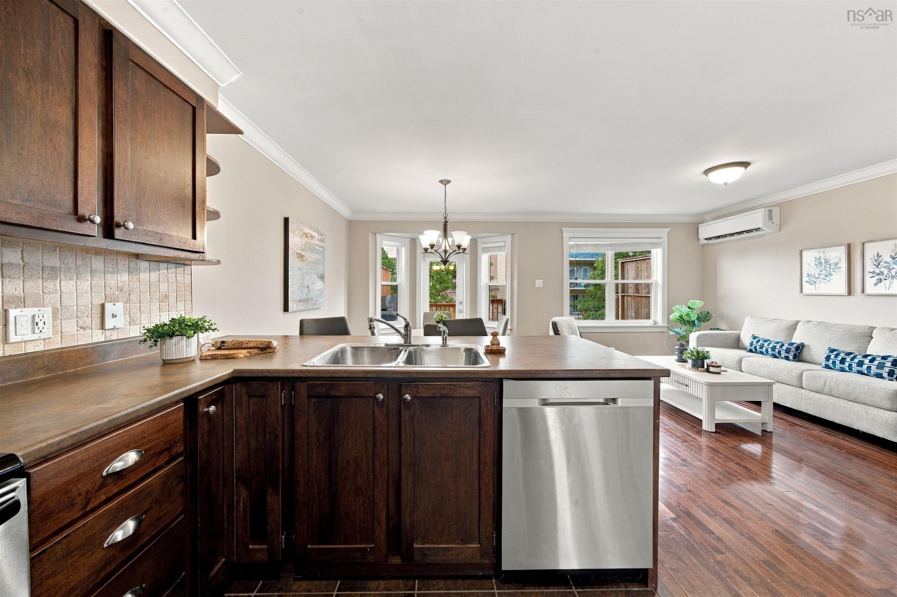 150 Transom Drive, Halifax, NS (MLS® 202625460) — Open-concept living area featuring wood-finish flooring, dark wood cabinetry, a stainless steel dishwasher, and crown molding