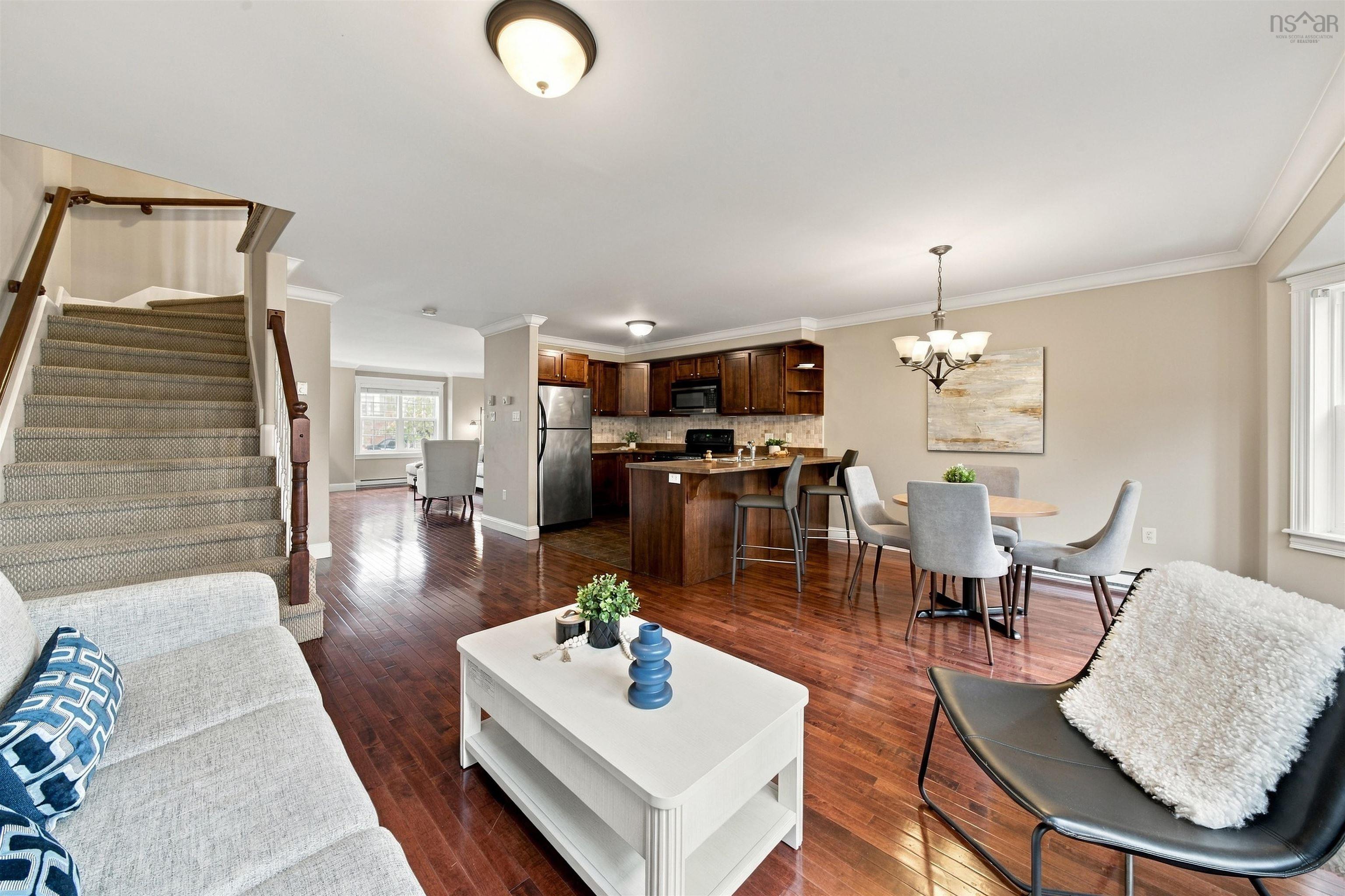 150 Transom Drive, Halifax, NS (MLS® 202625460) — Hardwood flooring throughout, kitchen with wood cabinetry and stainless steel appliances, dining area with chandelier, staircase with carpeted treads and wood handrail, and recessed lighting