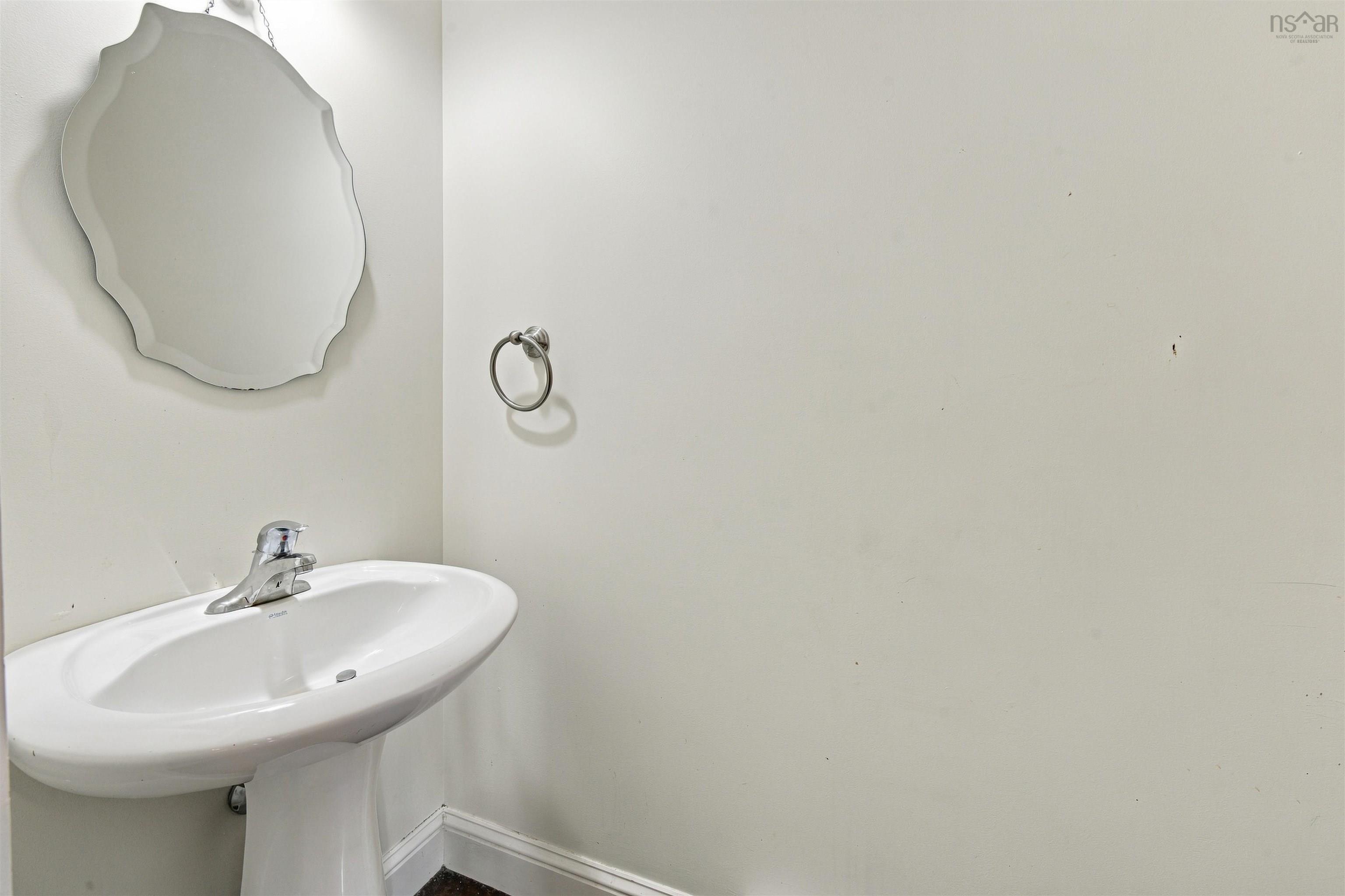 150 Transom Drive, Halifax, NS (MLS® 202625460) — Powder room featuring a curved pedestal sink with chrome faucet, scalloped-edge mirror with wall-mounted hardware, and clean white finishes throughout