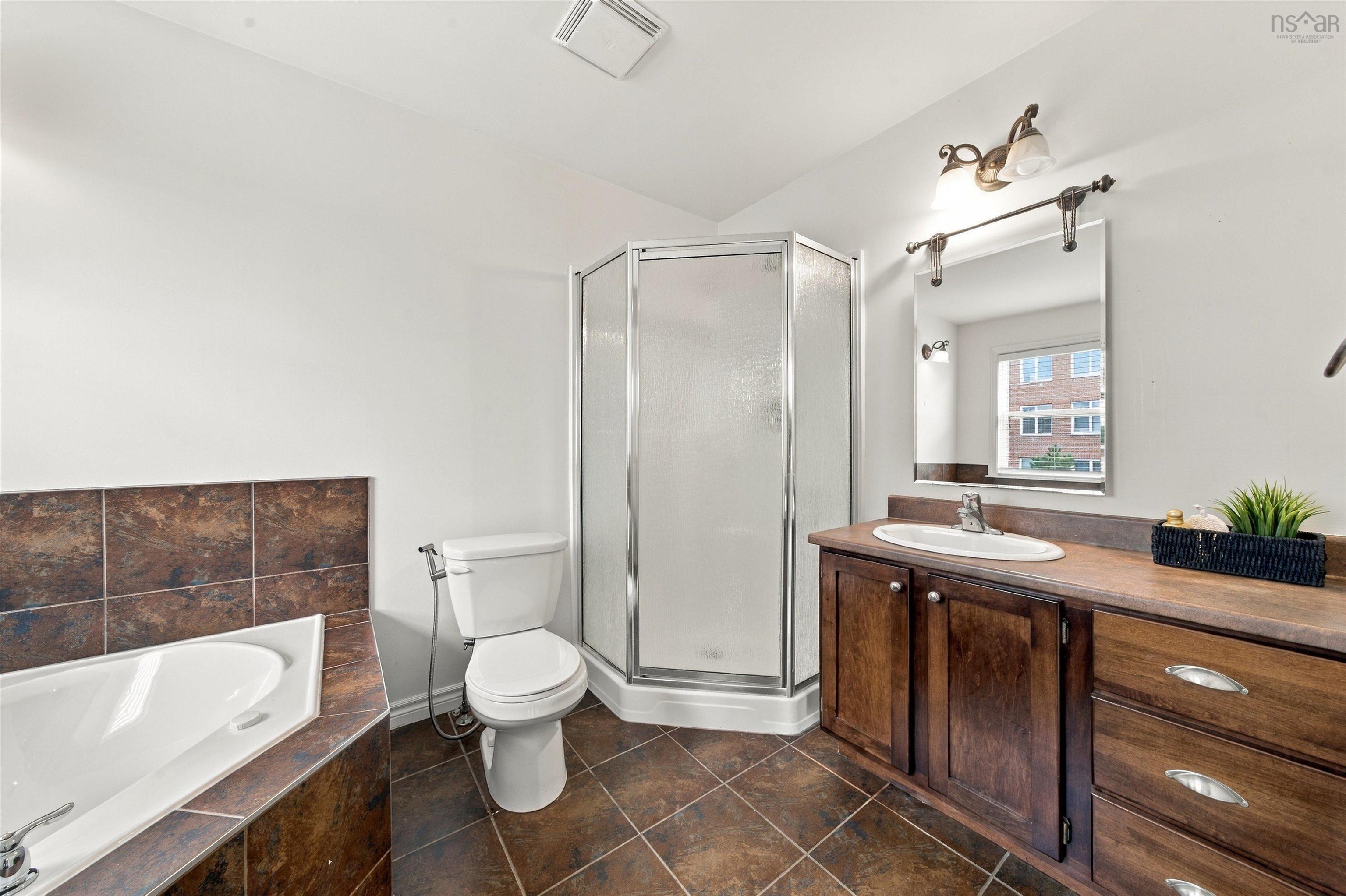 150 Transom Drive, Halifax, NS (MLS® 202625460) — Spacious bathroom featuring a corner shower, separate bathtub with tiled surround, wood-finish vanity with an integrated sink, and broad tile flooring