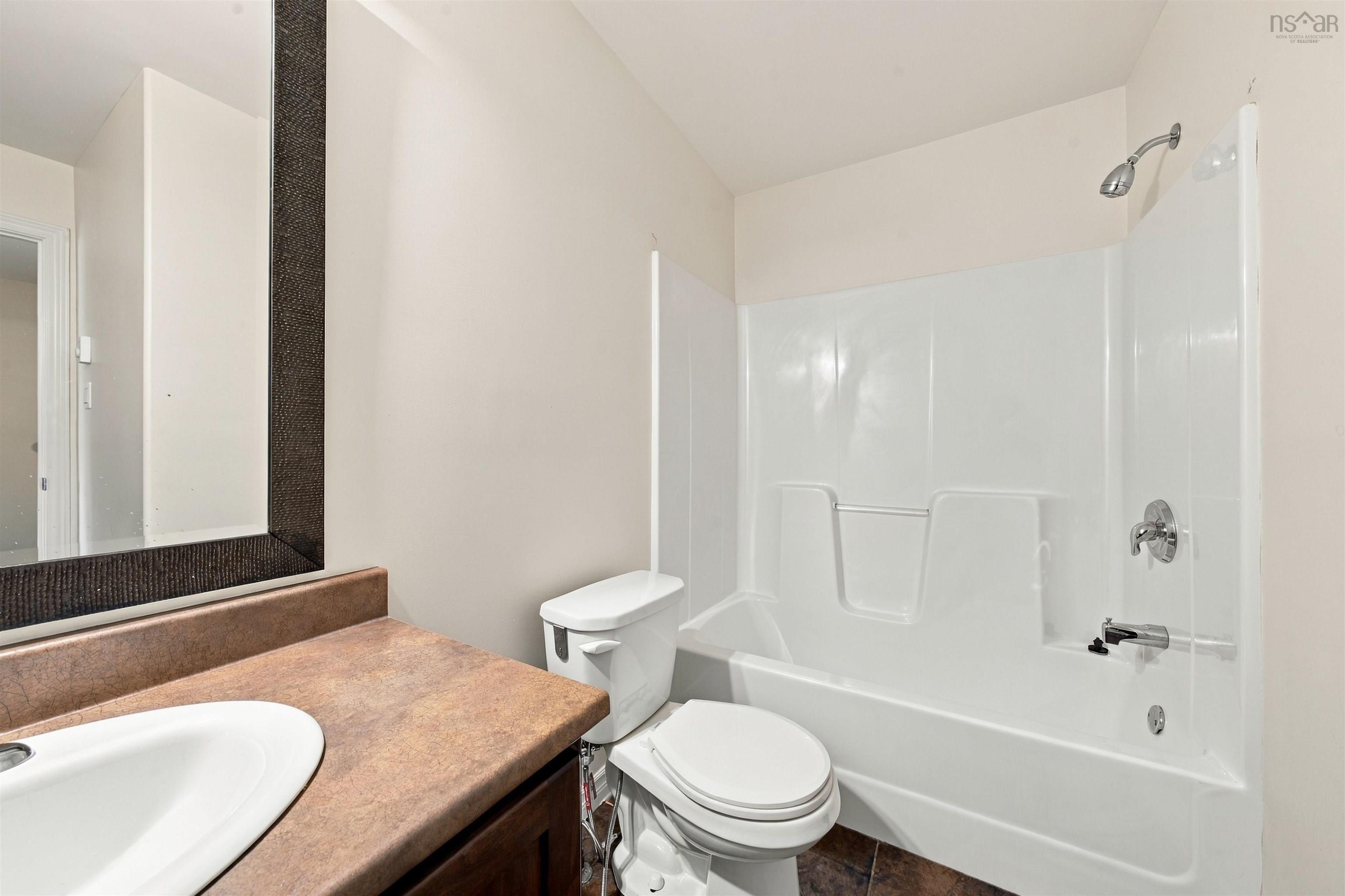 150 Transom Drive, Halifax, NS (MLS® 202625460) — Bathroom featuring a vanity with an integrated sink, a dark countertop, a toilet, and a combination tub and shower with a white surround