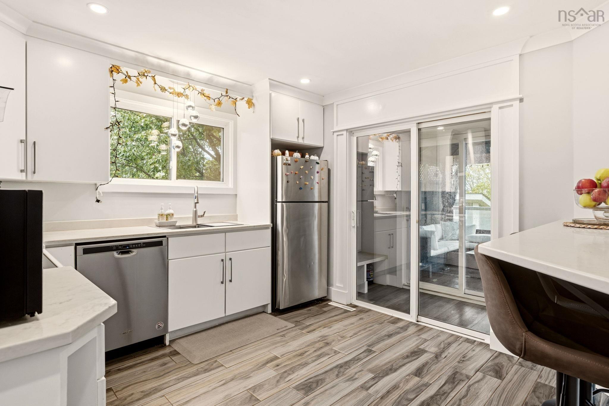 25 Circle Drive, Halifax, NS (MLS® 202625881) — Kitchen featuring white cabinetry, wood-finish flooring, quartz-surfaced countertops, stainless steel appliances, and sliding glass doors