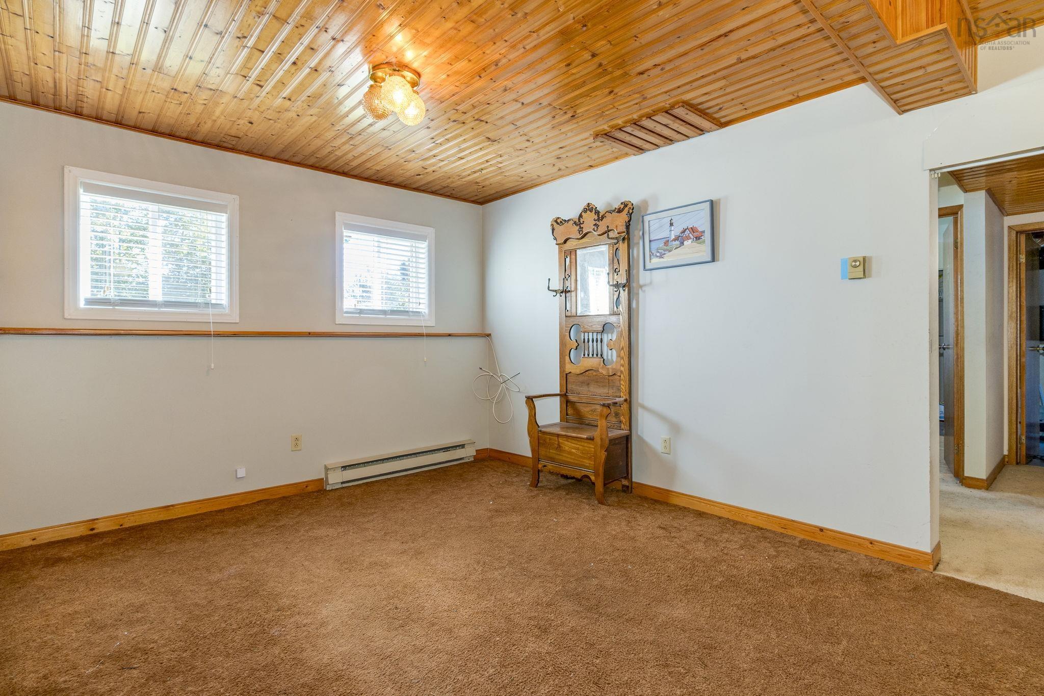 128 Doherty Drive, Lawrencetown, NS (MLS® 202625891) — Tongue-and-groove wood plank ceiling, dual windows with horizontal blinds, wood chair rail, and wall-mounted lighting fixture