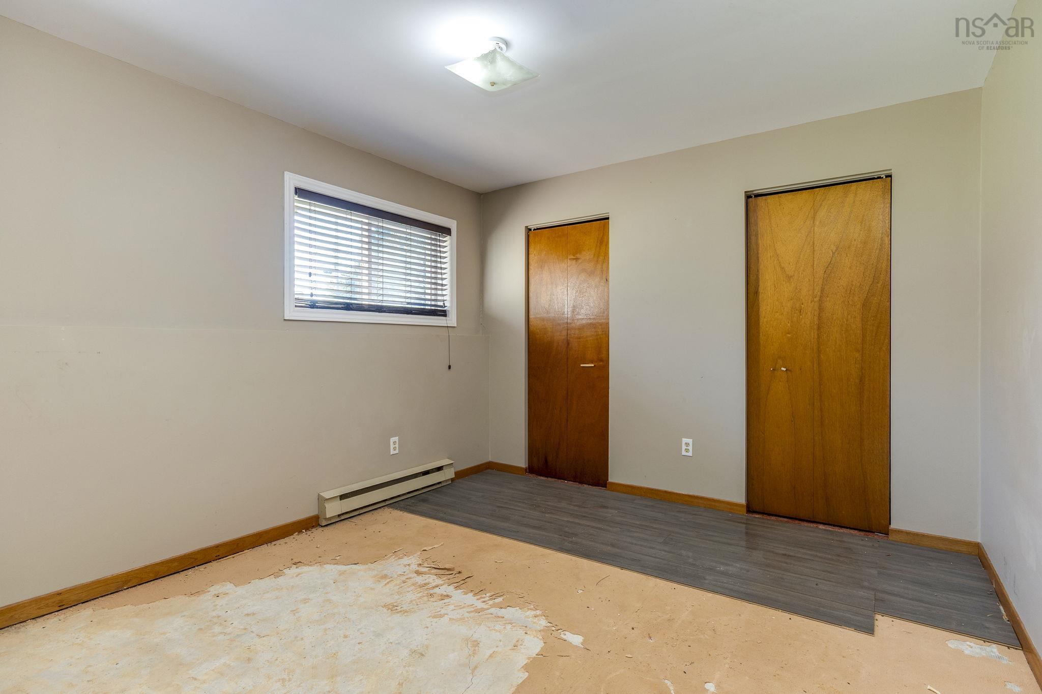 128 Doherty Drive, Lawrencetown, NS (MLS® 202625891) — Room featuring wood-finish interior doors, a rectangular window with horizontal blinds, and grey wood-finish flooring