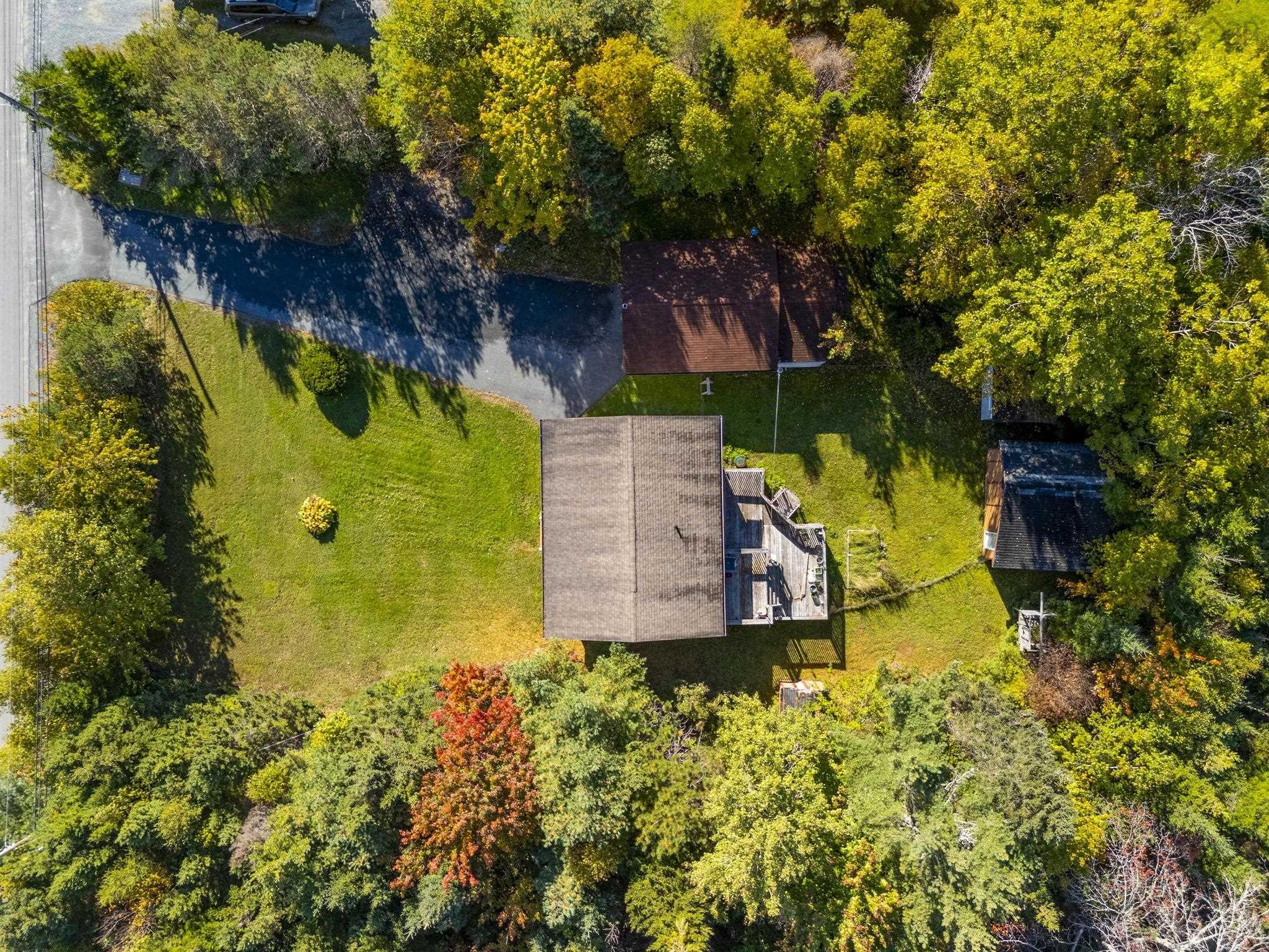 128 Doherty Drive, Lawrencetown, NS (MLS® 202625891) — Aerial perspective featuring a spacious lot, asphalt driveway, detached structure, and wooded perimeter