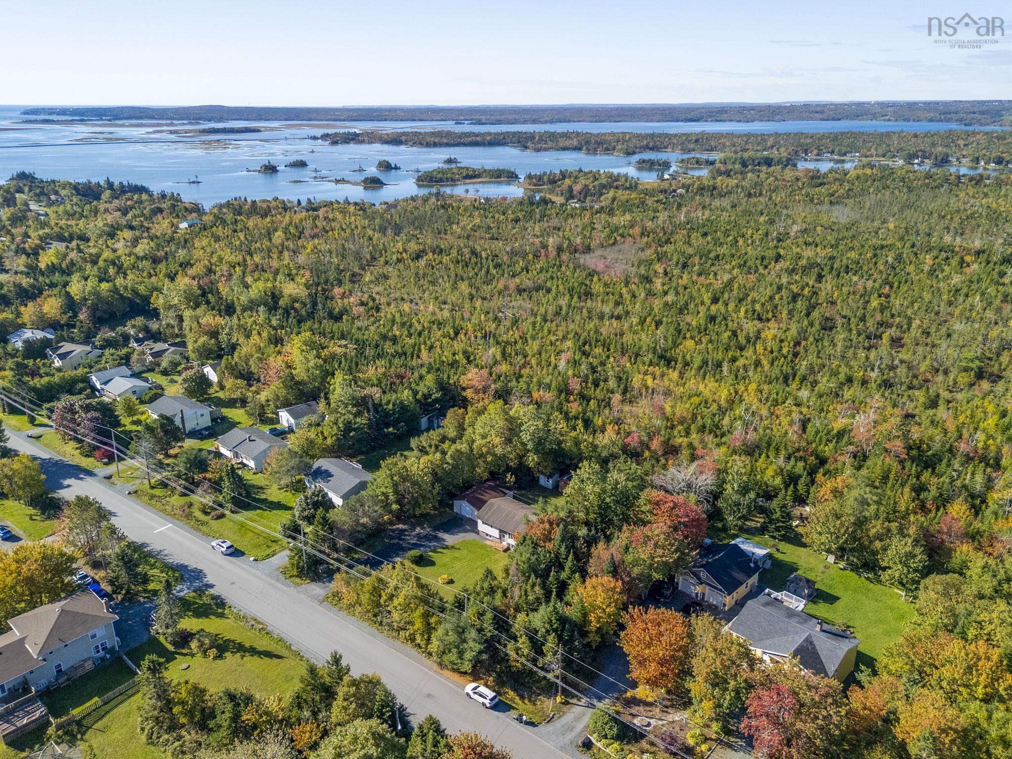 128 Doherty Drive, Lawrencetown, NS (MLS® 202625891) — Aerial perspective of property featuring dense woodland acreage, expansive water frontage, and mature deciduous trees