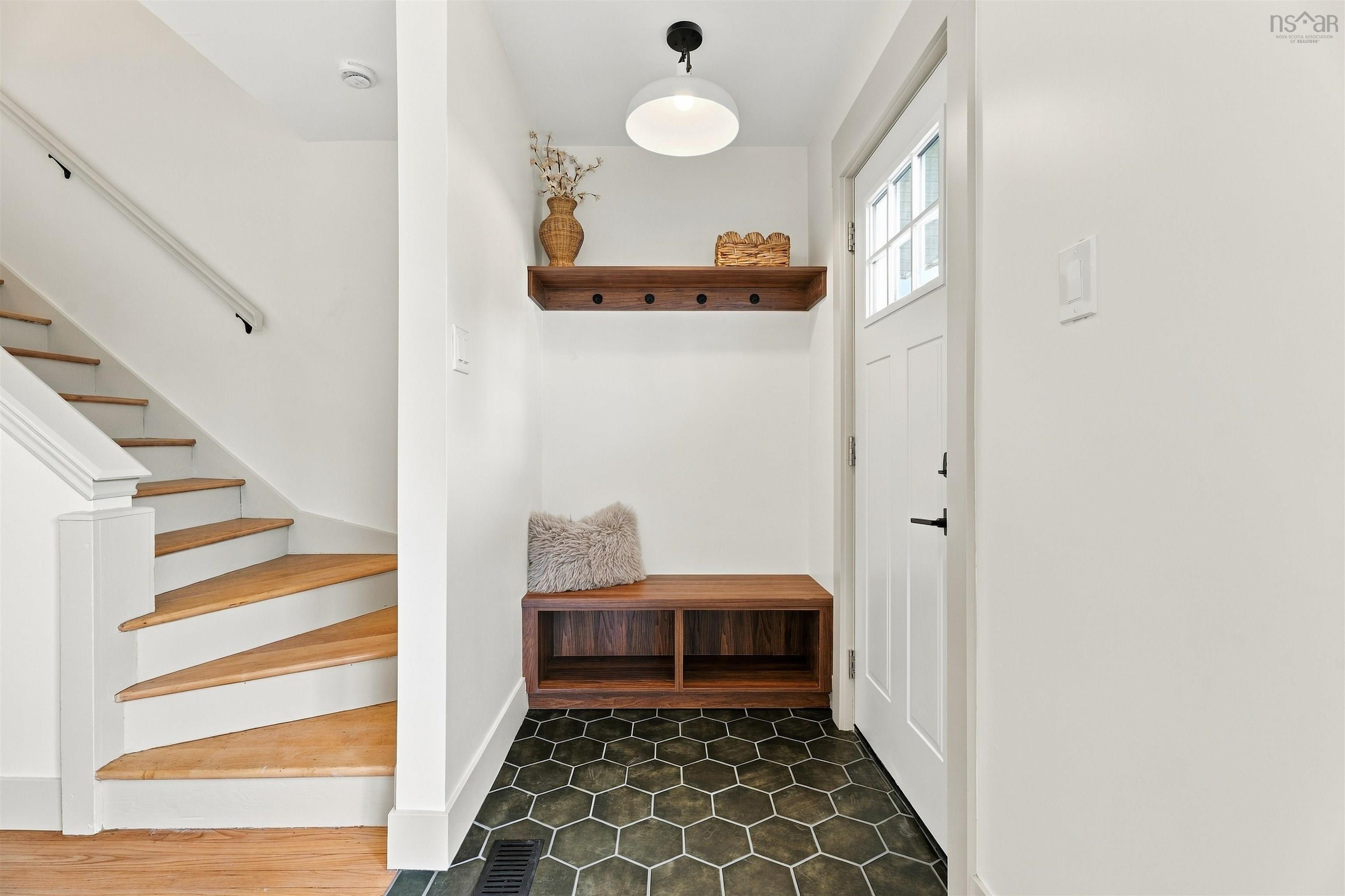 74 1/2 Belle Vista Drive, Dartmouth, NS (MLS® 202625912) — Entryway featuring hexagon tile flooring, built-in wooden bench with lower storage, matching wall-mounted shelf with coat hooks, pendant lighting, and a staircase with wood treads