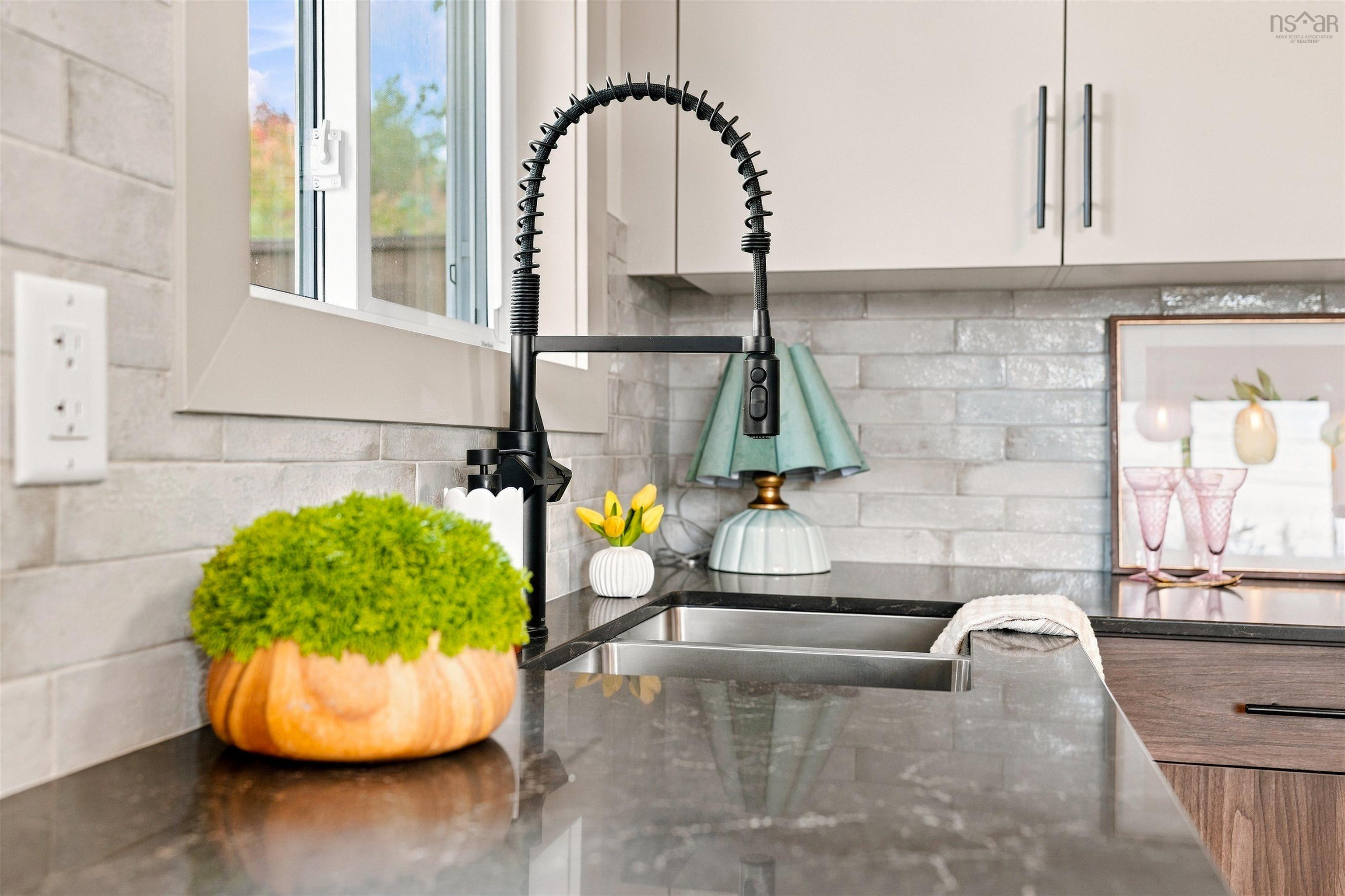 74 1/2 Belle Vista Drive, Dartmouth, NS (MLS® 202625912) — Kitchen featuring a stainless steel undermount sink, matte black gooseneck faucet, stone-finish countertops, light-toned cabinetry with linear hardware, and a subway-style tile backsplash