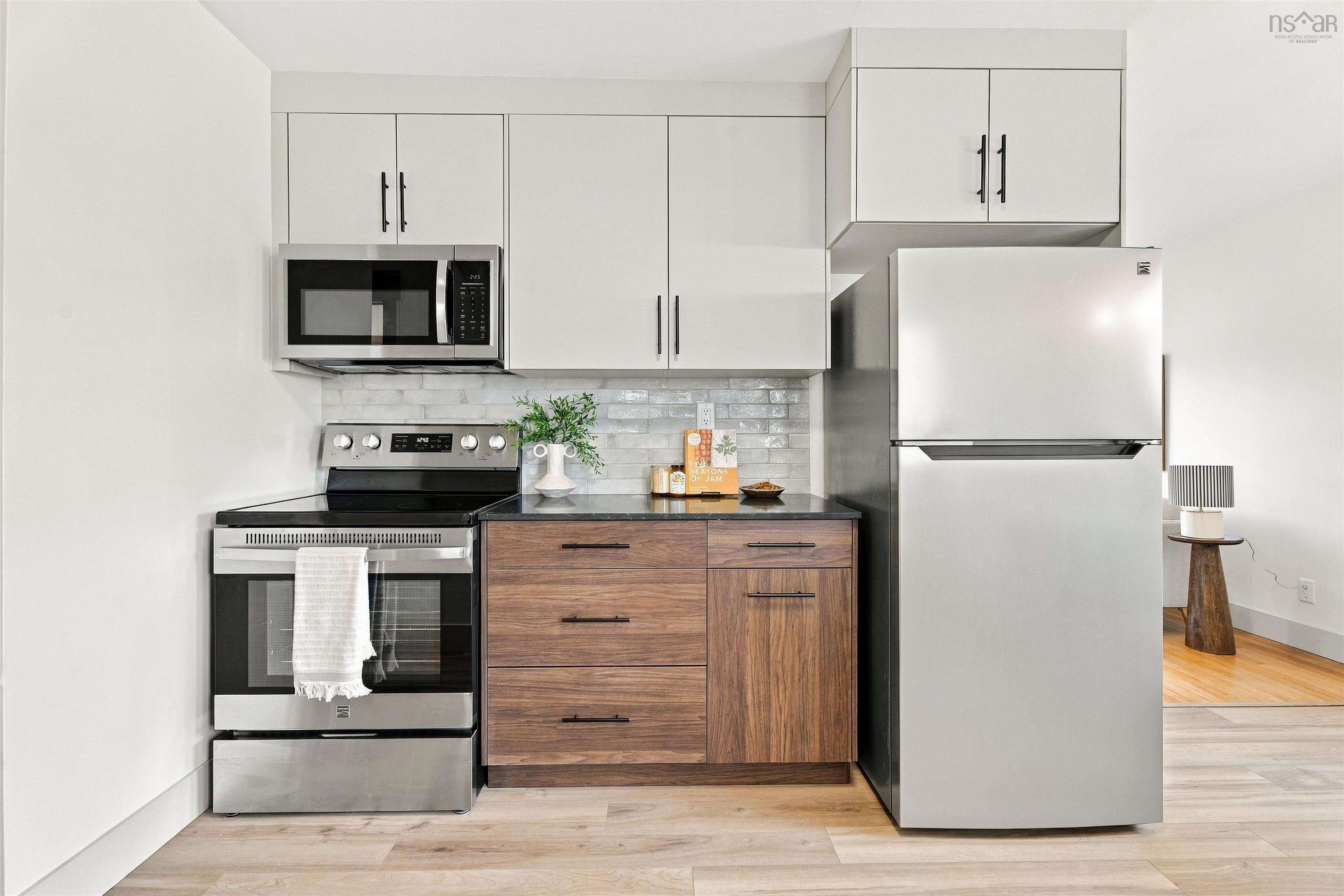 74 1/2 Belle Vista Drive, Dartmouth, NS (MLS® 202625912) — Kitchen featuring stainless steel appliances, light wood-finish cabinetry, dark stone-finish countertops, textured subway tile backsplash, and matte black hardware