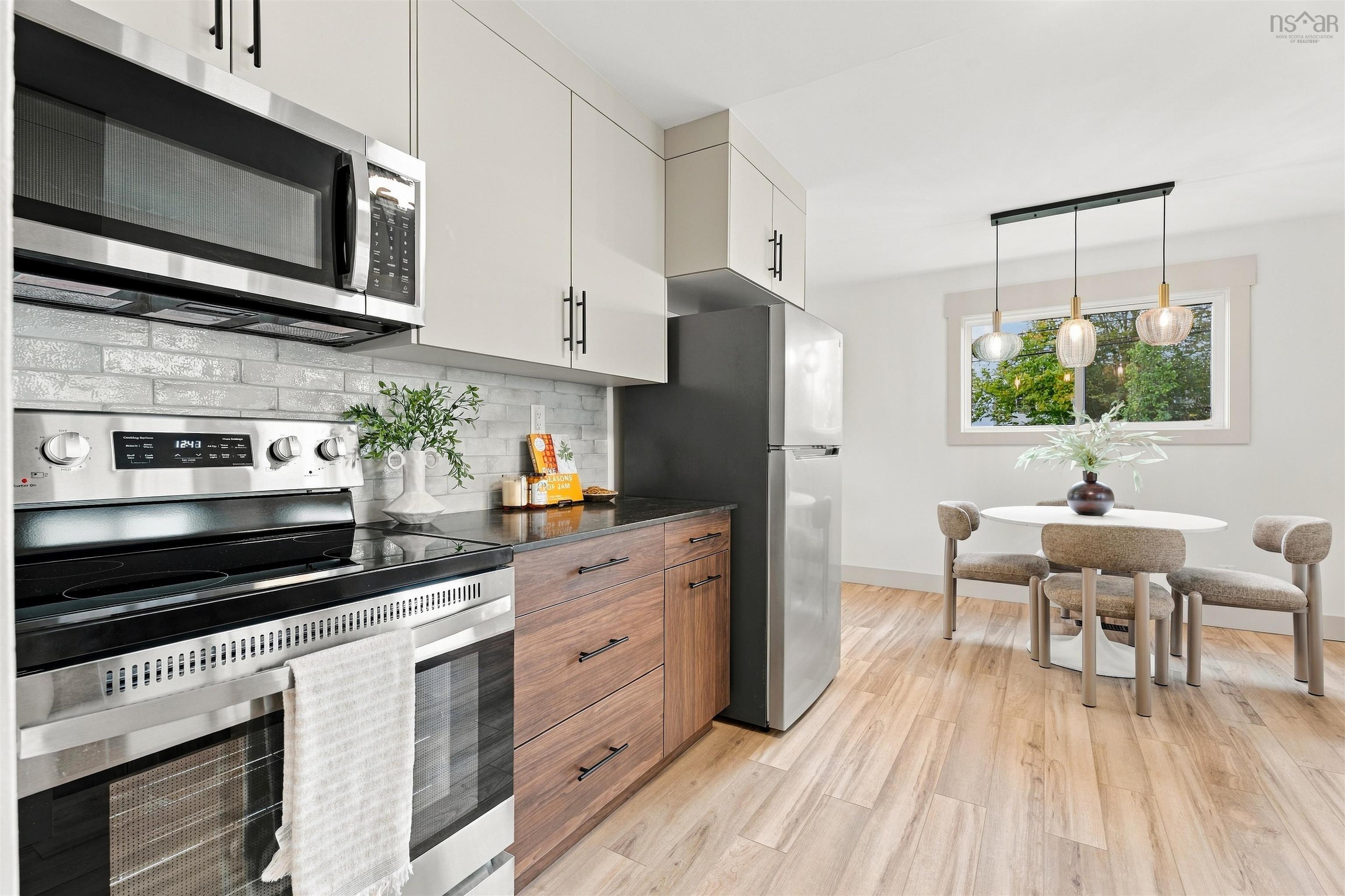 74 1/2 Belle Vista Drive, Dartmouth, NS (MLS® 202625912) — Kitchen featuring two-tone cabinetry with wood-finish lower drawers, light-toned upper cabinets, stainless steel appliances, a textured tile backsplash, and wood-finish flooring