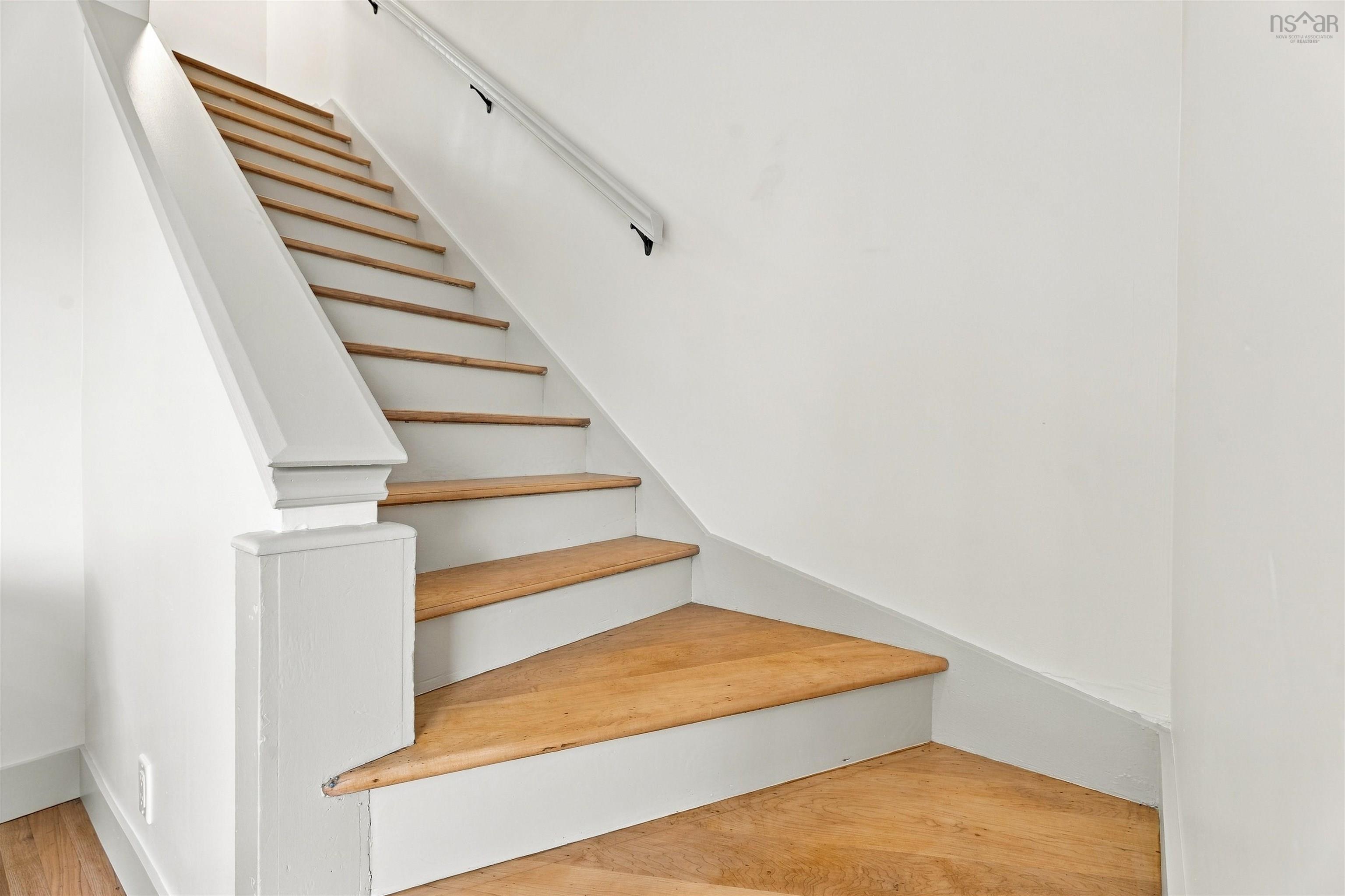 74 1/2 Belle Vista Drive, Dartmouth, NS (MLS® 202625912) — Staircase featuring wood-finish treads, white painted risers, a wood-finish landing, and a white handrail