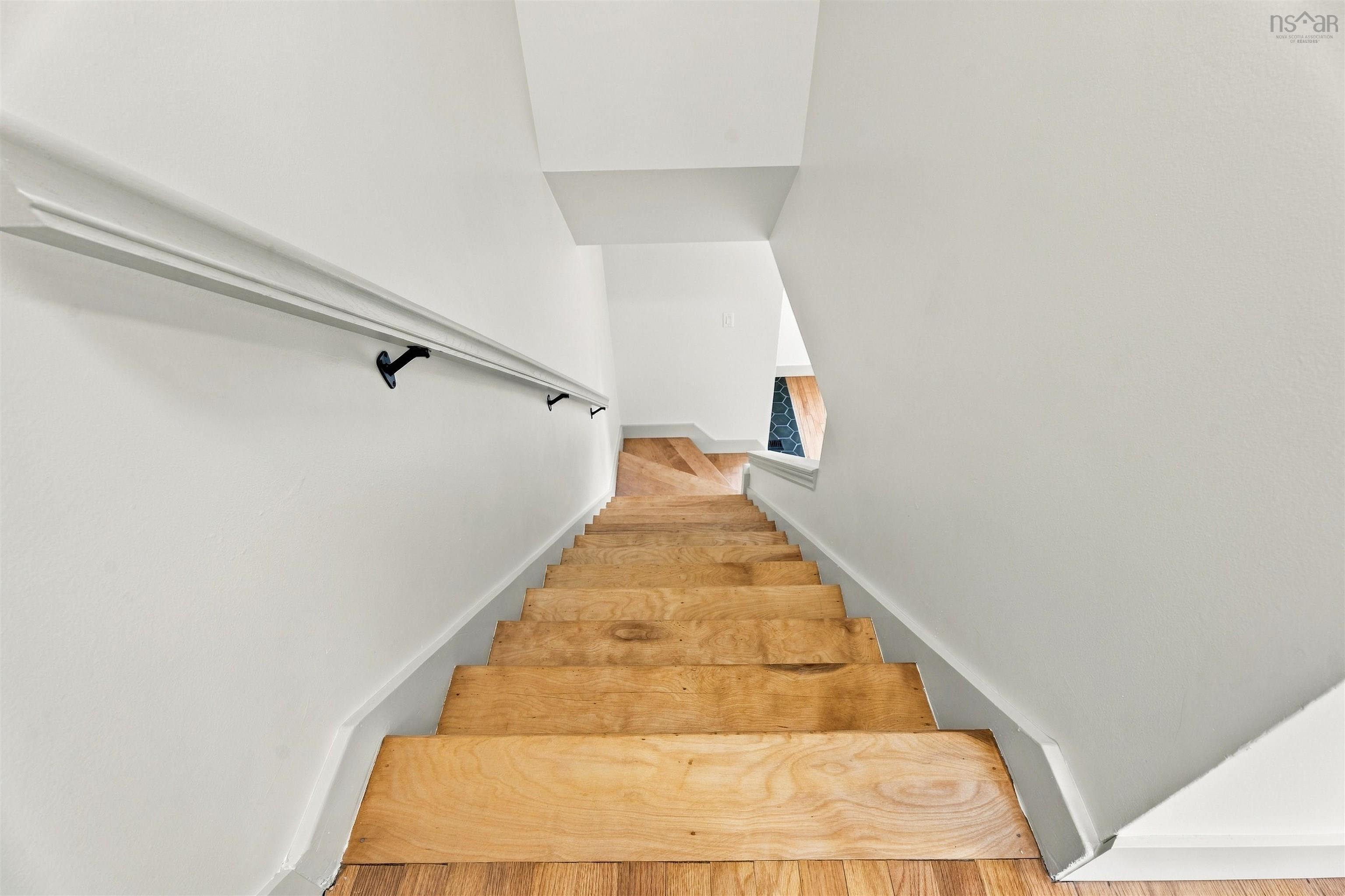 74 1/2 Belle Vista Drive, Dartmouth, NS (MLS® 202625912) — Staircase featuring natural wood-finish treads and a wall-mounted handrail with matte black hardware