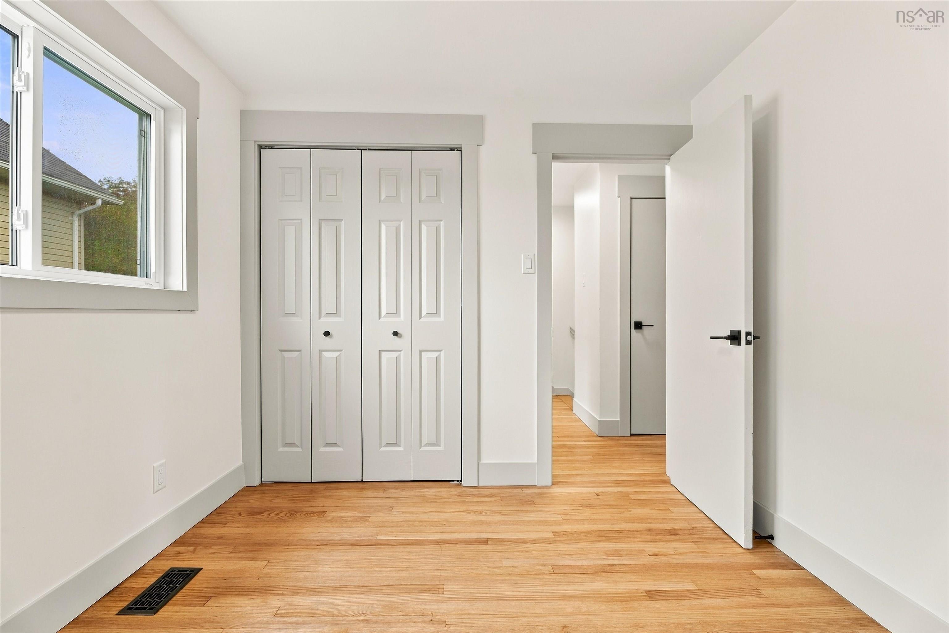 74 1/2 Belle Vista Drive, Dartmouth, NS (MLS® 202625912) — Interior space featuring wood-finish flooring, white paneled bi-fold closet doors, minimalist flat-panel interior doors, and matte black hardware