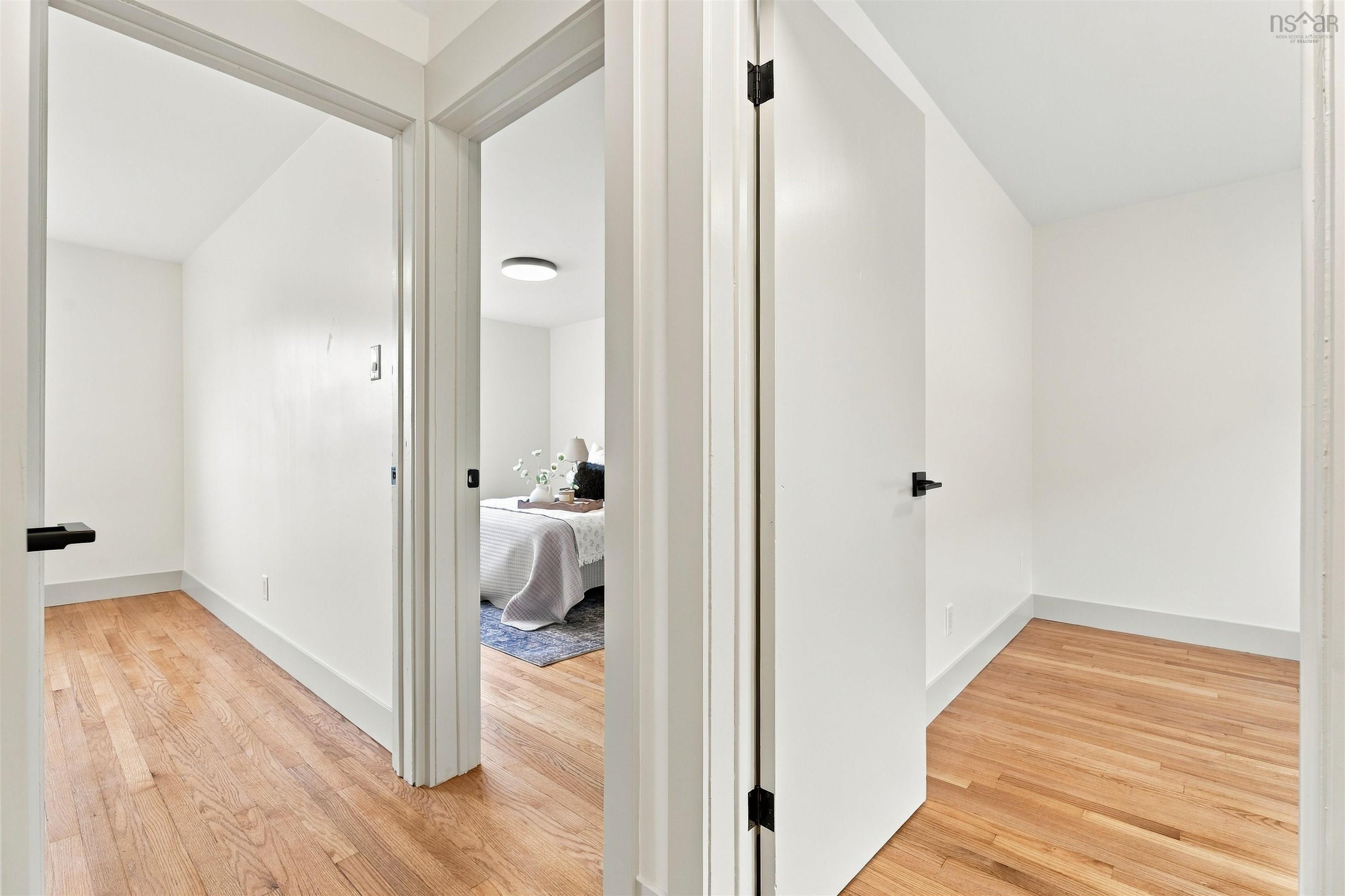 74 1/2 Belle Vista Drive, Dartmouth, NS (MLS® 202625912) — Hallway featuring wood-finish flooring, crisp white walls, and matte black door hardware