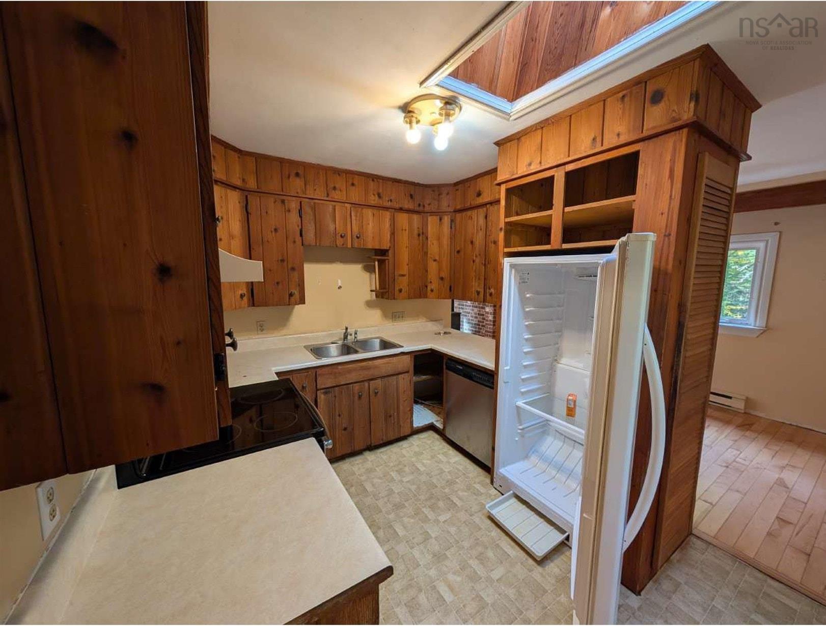 19 Foster Avenue, Fall River, NS (MLS® 202625937) — Kitchen featuring knotty wood cabinetry, a skylight, a stainless steel double-basin sink, and integrated overhead lighting