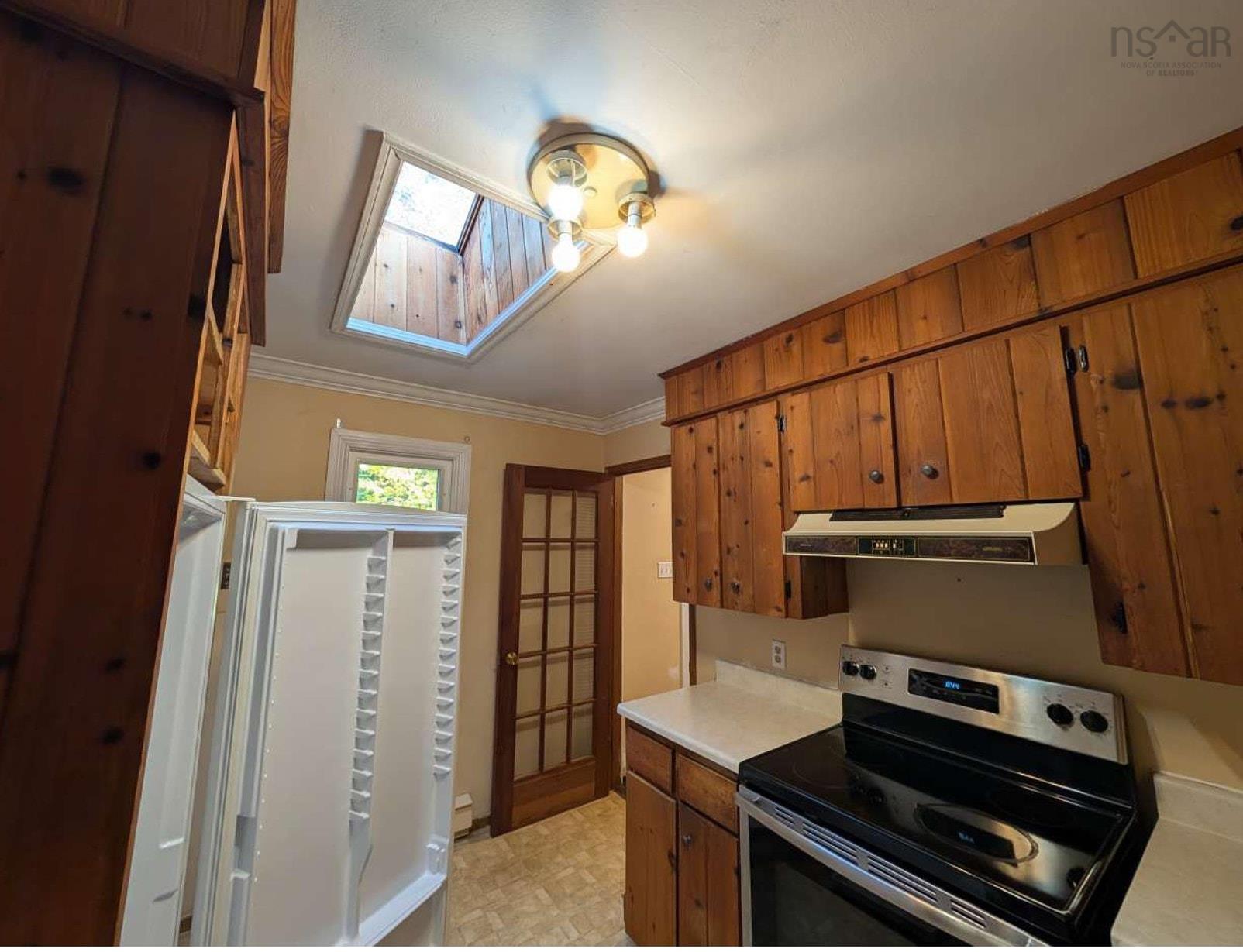 19 Foster Avenue, Fall River, NS (MLS® 202625937) — Kitchen featuring natural wood cabinetry, stainless steel range with integrated hood, skylight, and multi-pane wood-framed door