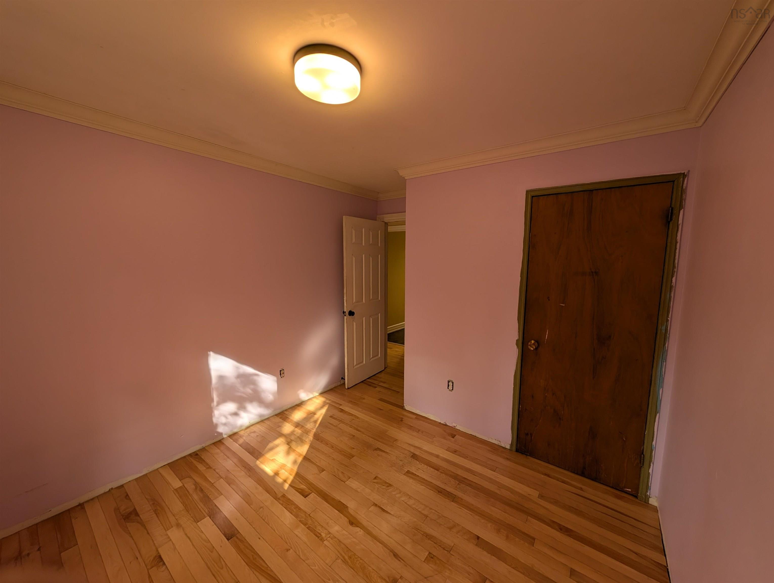 19 Foster Avenue, Fall River, NS (MLS® 202625937) — Room featuring wood-finish flooring, crown molding, a flush-mount ceiling light fixture, and a solid wood door